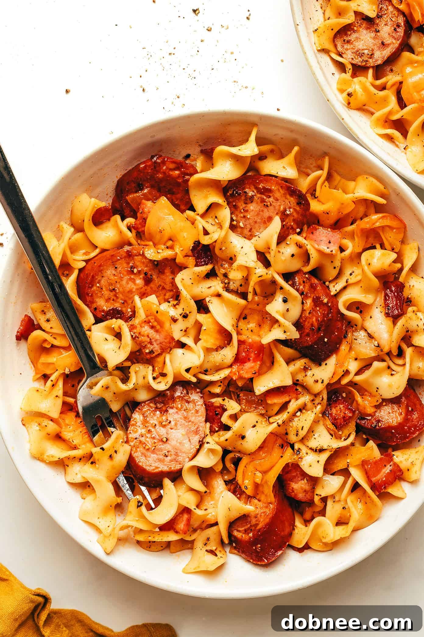 A close-up shot of a bowl of Kielbasa and Cabbage Noodles, showcasing the rich colors of sausage, tender cabbage, and egg noodles coated in a rich, savory sauce.