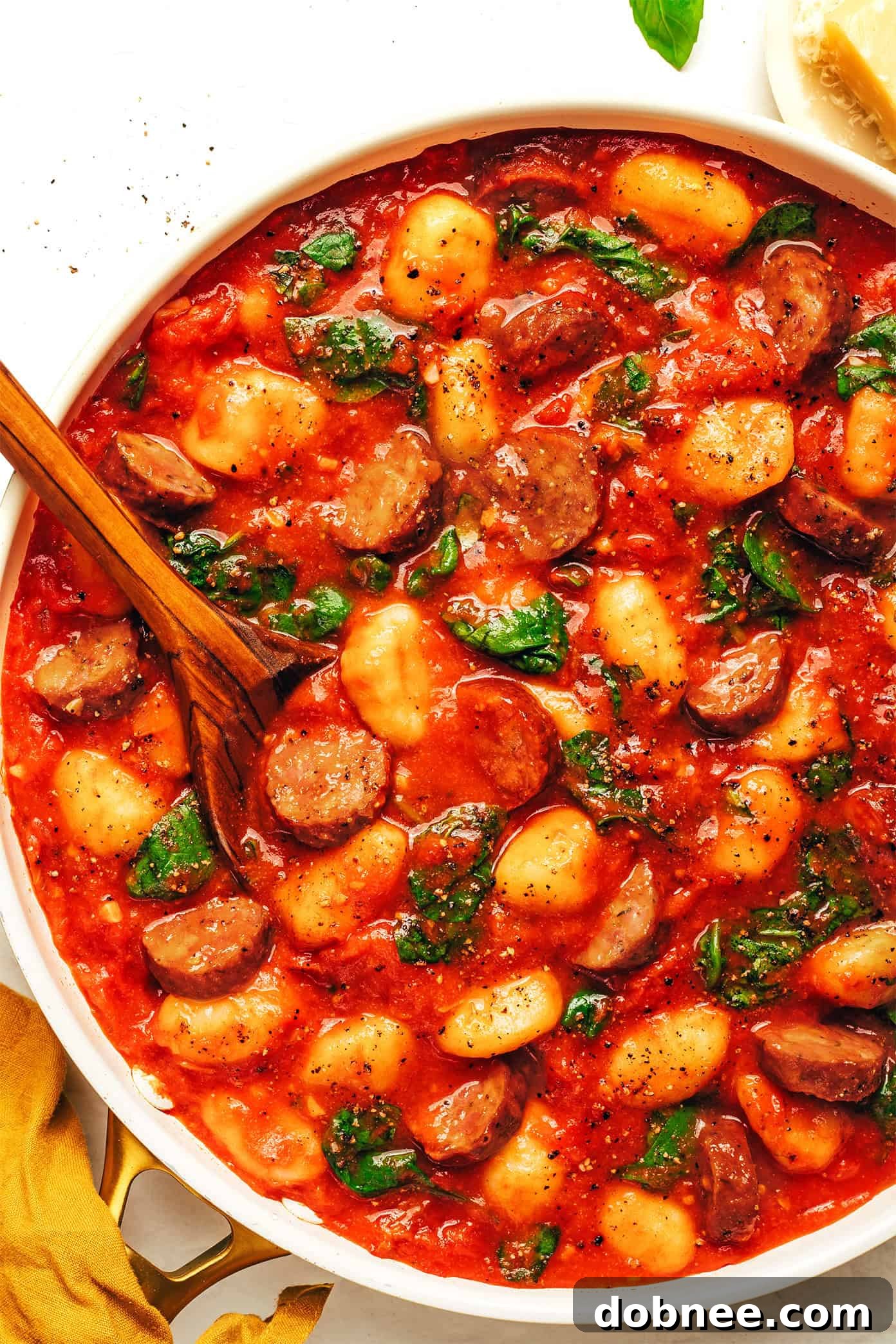 Sausage and Gnocchi Marinara served in a bowl, garnished with fresh basil and Parmesan.