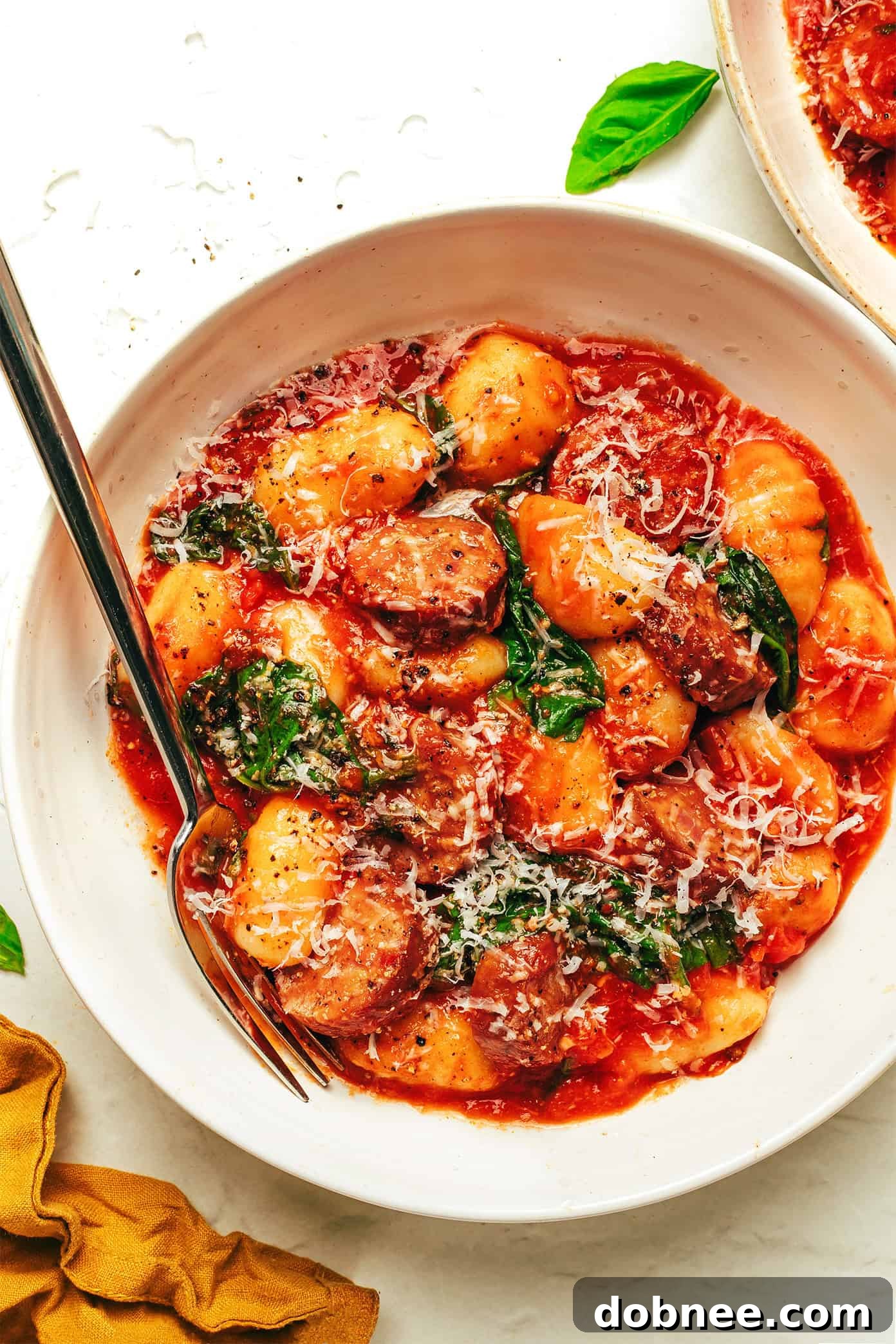 Full spread of Sausage and Gnocchi Marinara with fresh ingredients and a glass of wine.