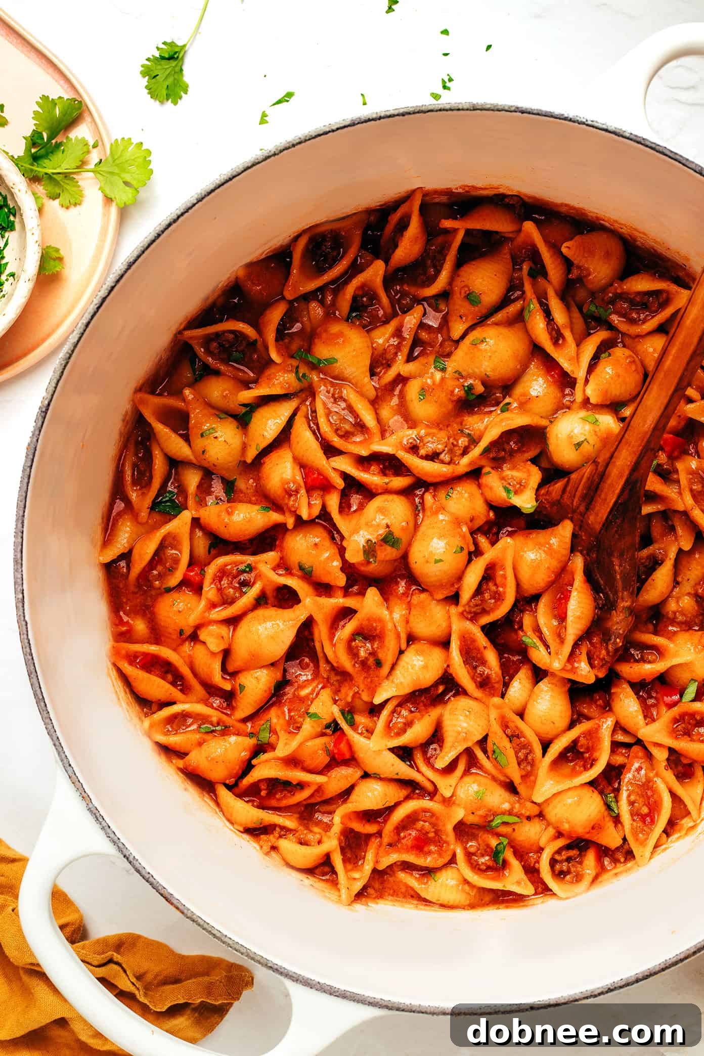 A side view of a serving of One Pot Cheesy Taco Pasta in a bowl, garnished with fresh cilantro and avocado, ready to eat.