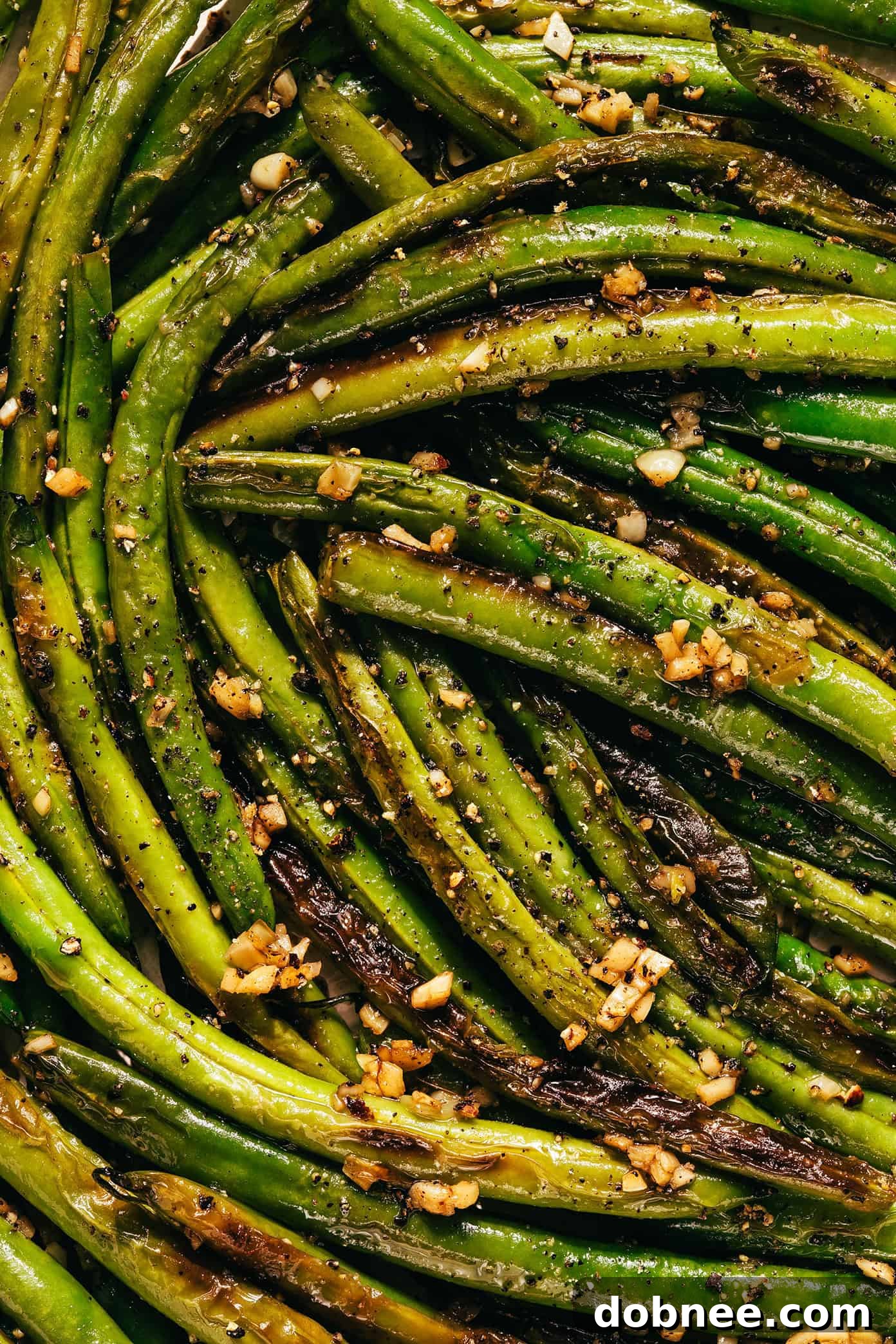 Platter of perfectly cooked garlic green beans with lemon wedges