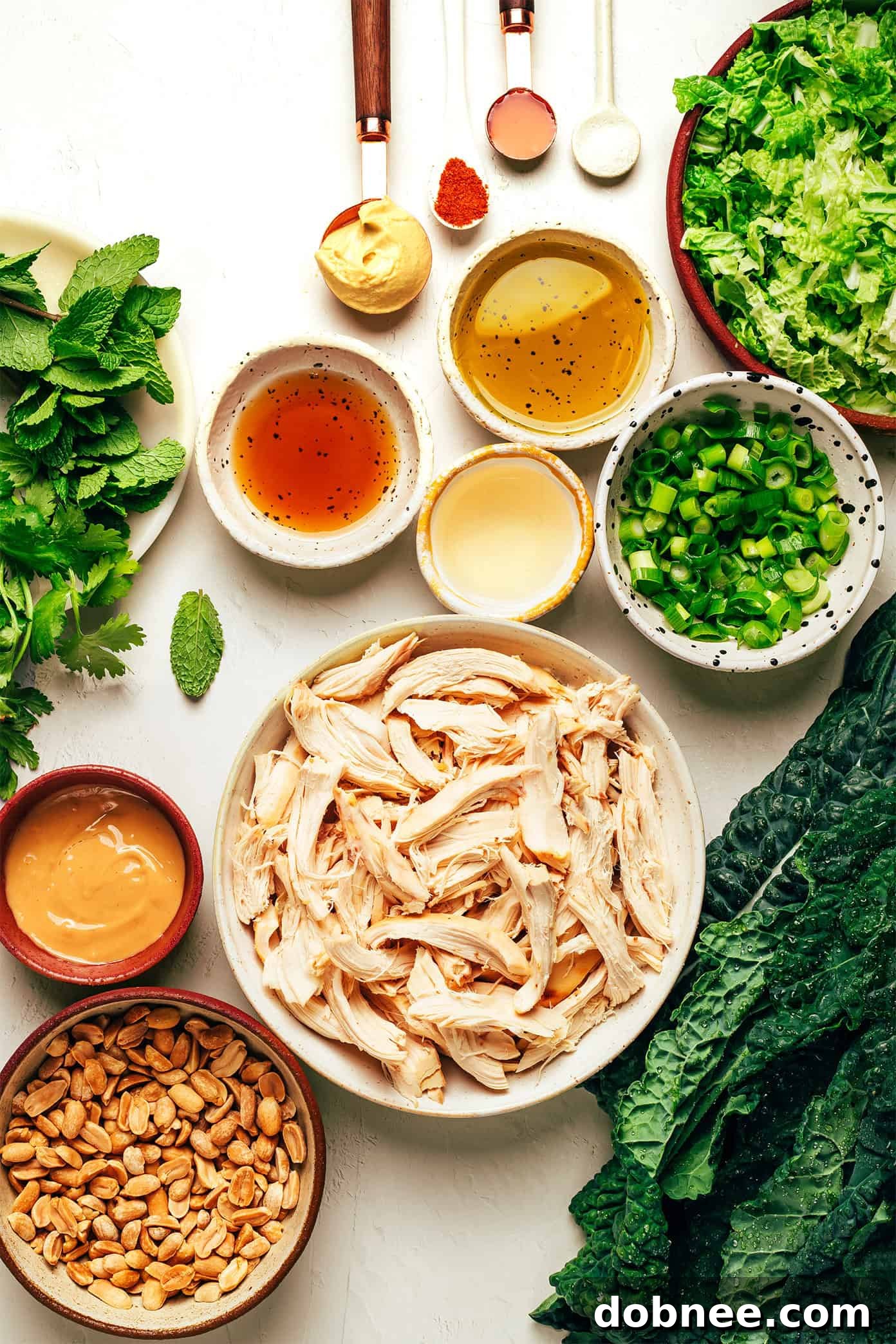 A serving of Kale Peanut Chicken Salad in a bowl, showing the texture of the dressing and a fork ready to scoop