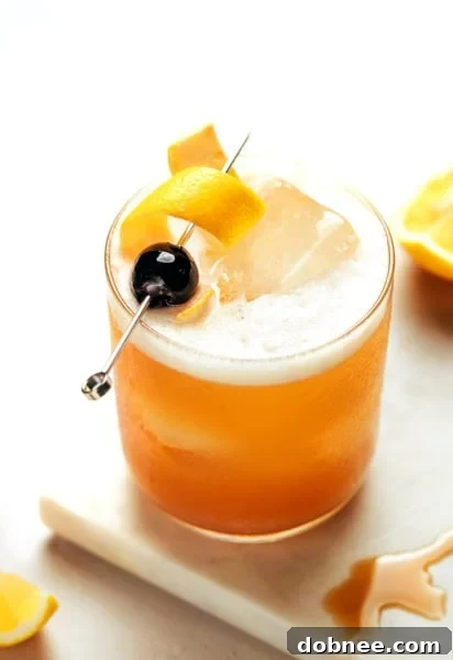 Amaretto Sour in a glass with a lemon twist and cherry.