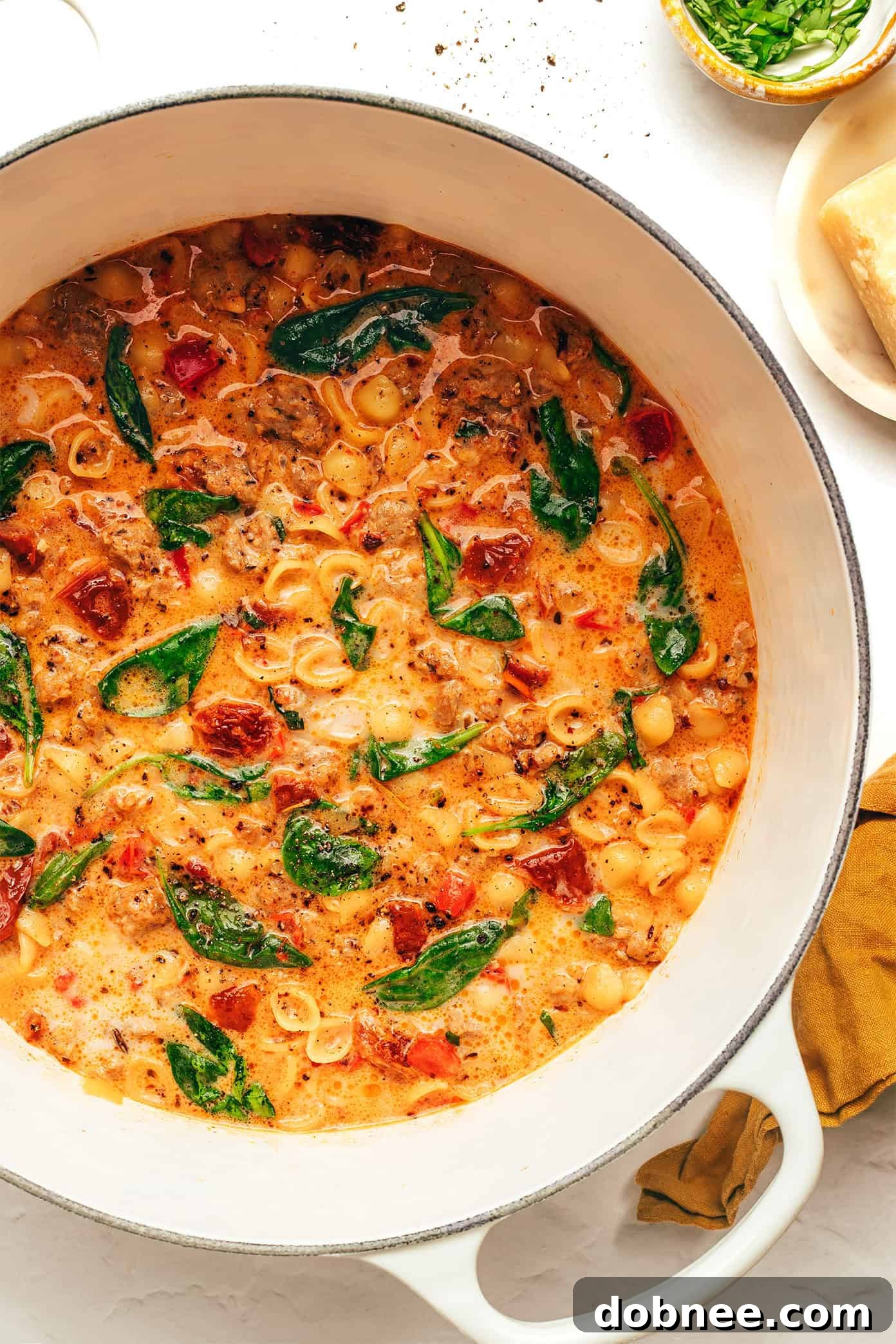 A large bowl of creamy Marry Me Italian Sausage Soup, garnished with fresh basil and Parmesan cheese, showcasing its rich texture and vibrant colors.