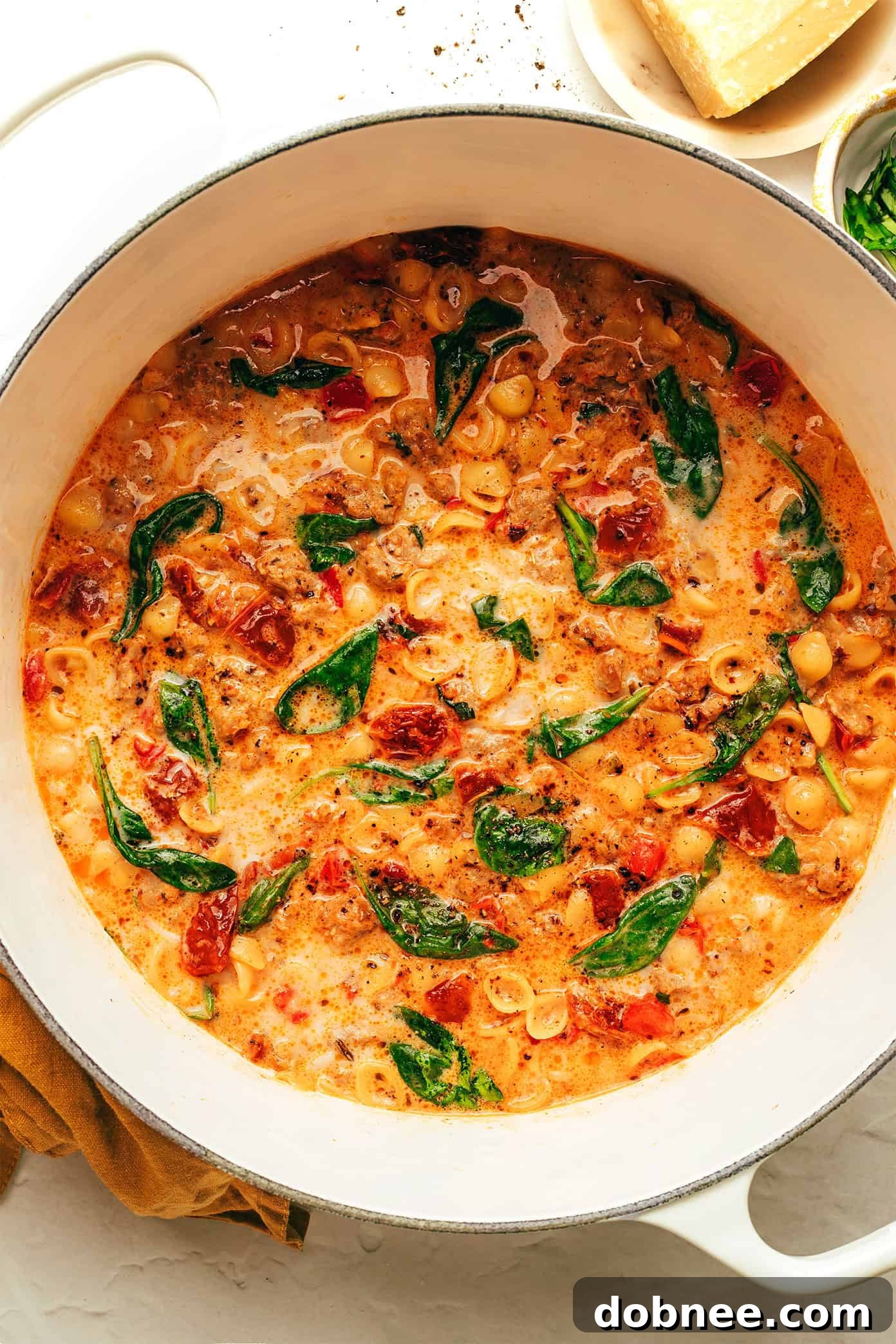 A serving of Marry Me Italian Sausage Soup with a rustic spoon, showcasing the rich, creamy broth and perfectly cooked pasta.