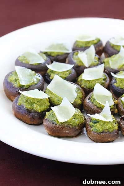 Close-up of baked pesto stuffed mushrooms garnished with pine nuts and cheese