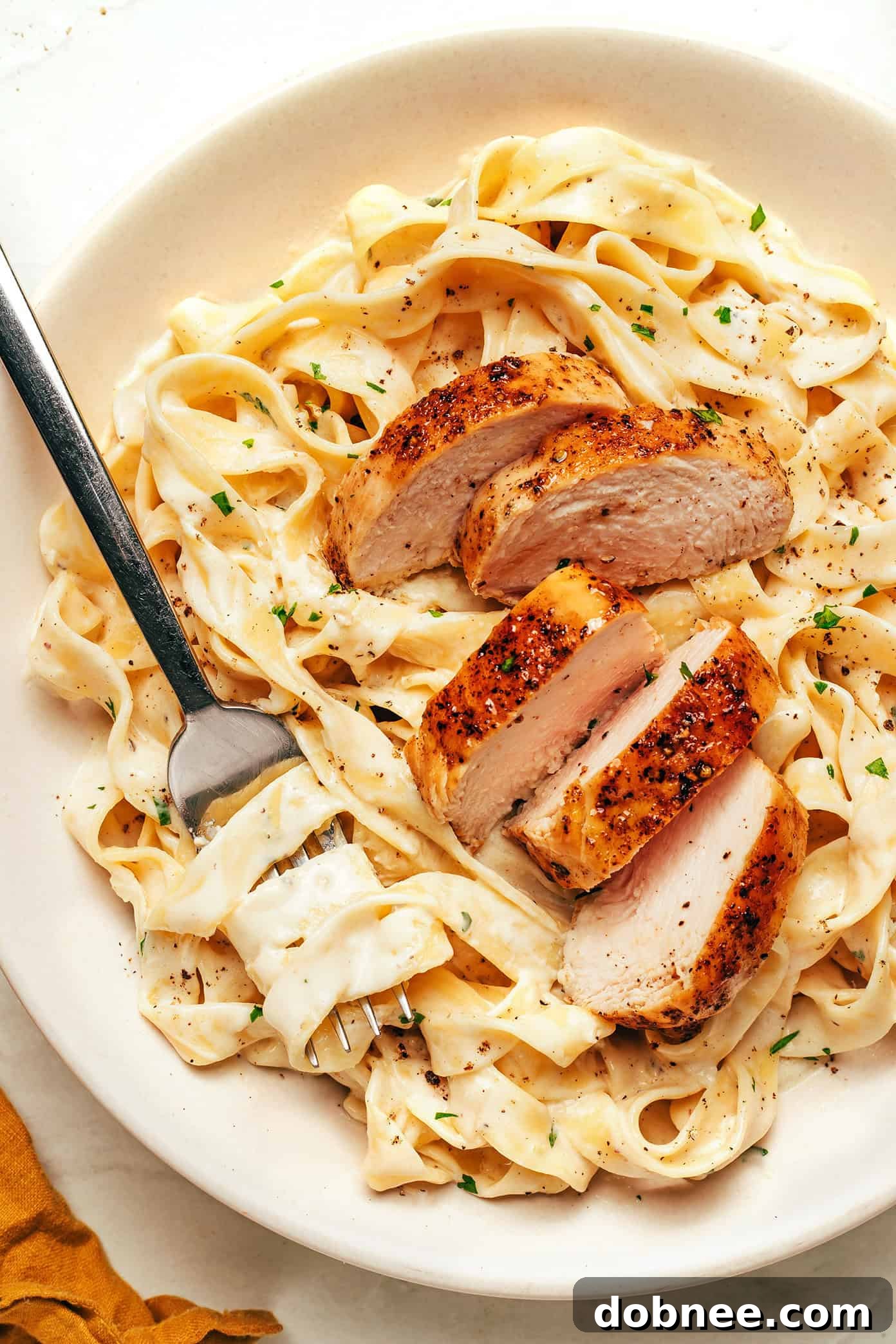 Creamy Chicken Fettuccine Alfredo served in a bowl, garnished with fresh parsley.
