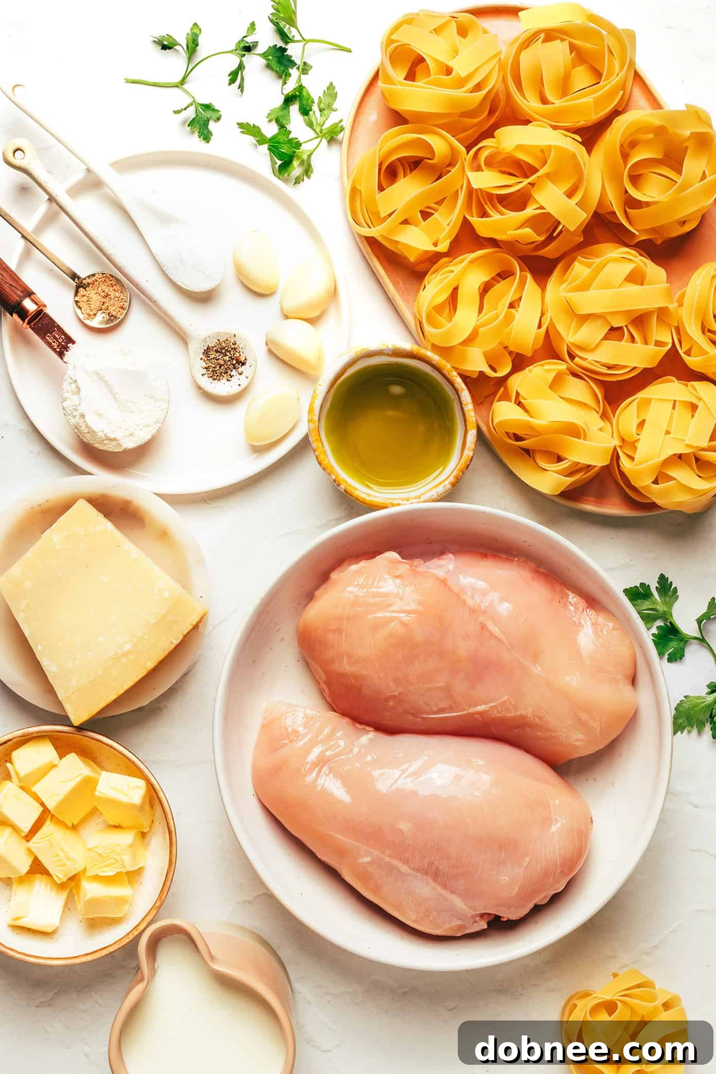 Close-up of uncooked fettuccine pasta, a block of Parmesan, and garlic cloves, ready for the Alfredo sauce preparation.