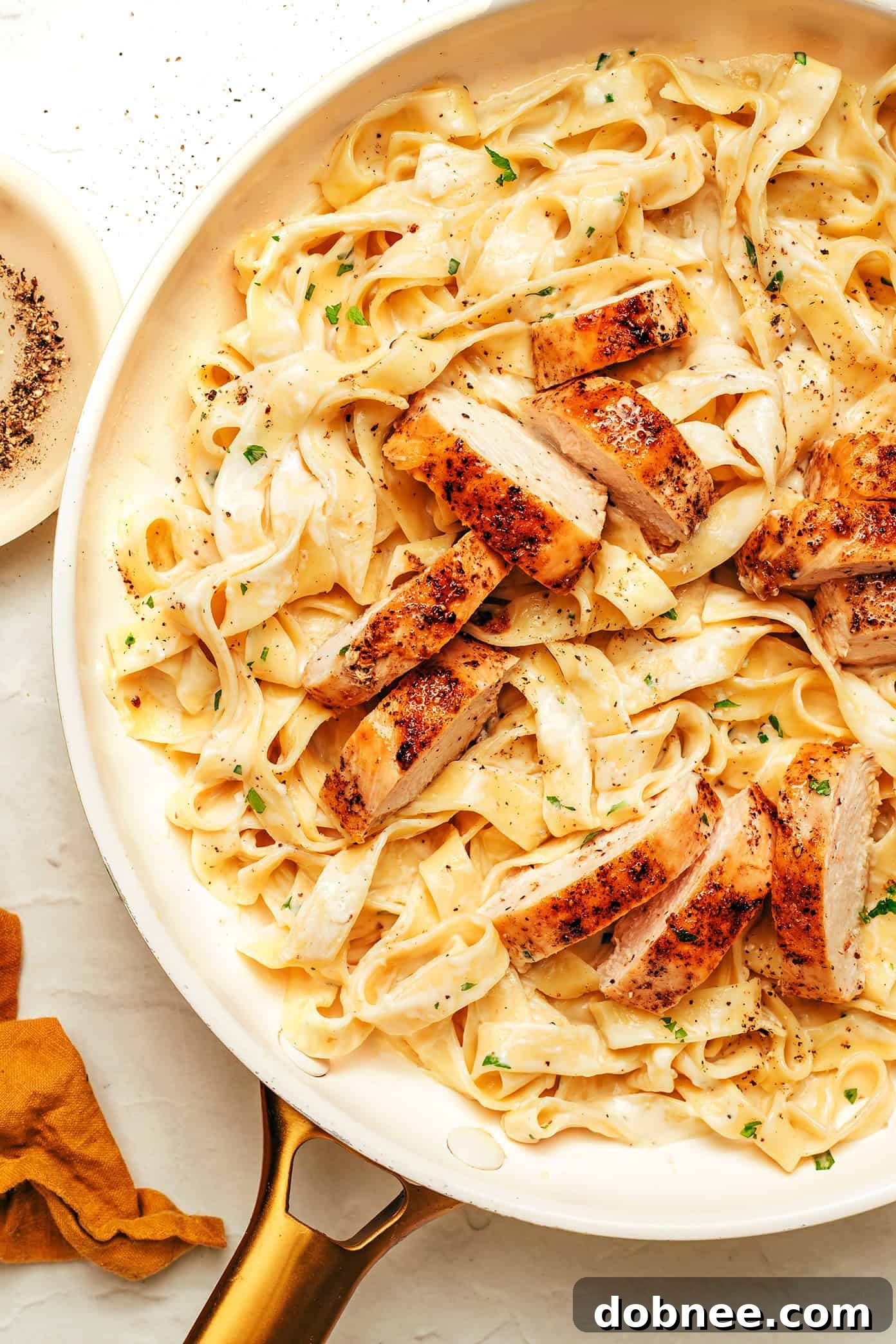 A close-up of a rustic wooden cutting board with a fine grater, garlic press, and ground nutmeg, representing kitchen tools and spices.