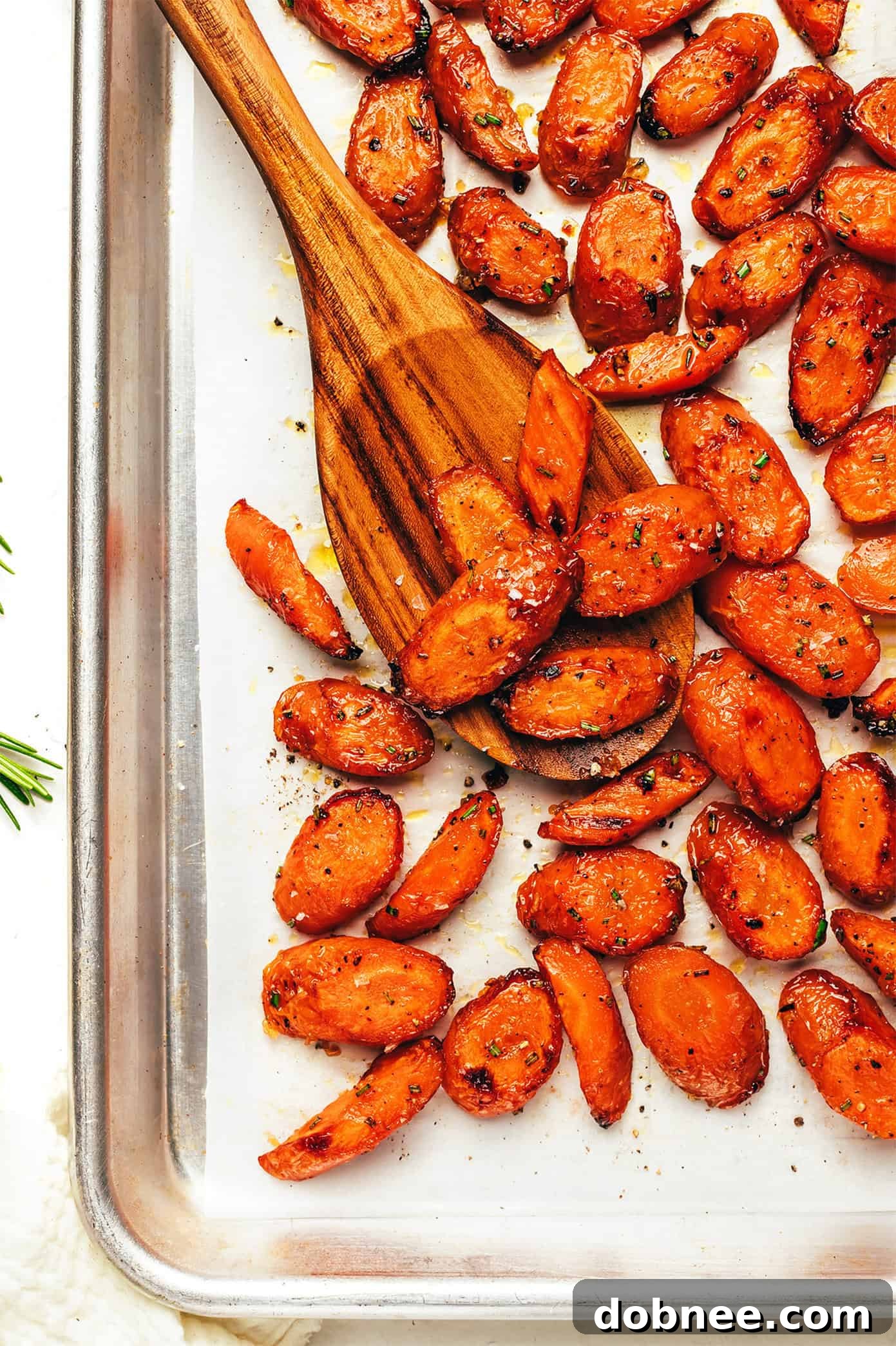 Beautifully roasted carrots glistening with honey butter glaze, sprinkled with fresh rosemary and sea salt, served on a rustic baking sheet.