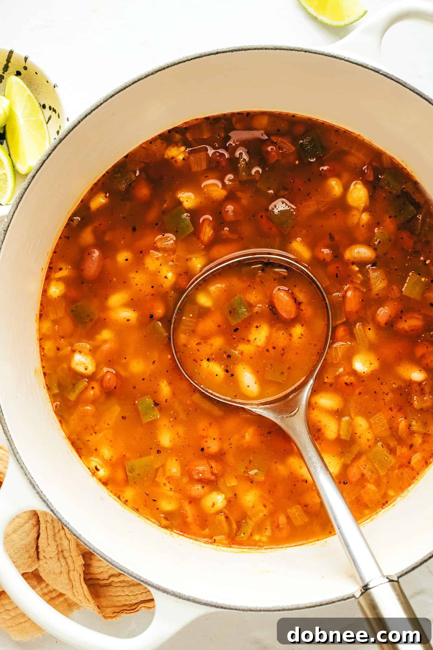 Plant-Powered Pozole 5 A hand holding a spoon, scooping a generous portion of vegetarian pozole from a bowl, garnished with fresh herbs and avocado.