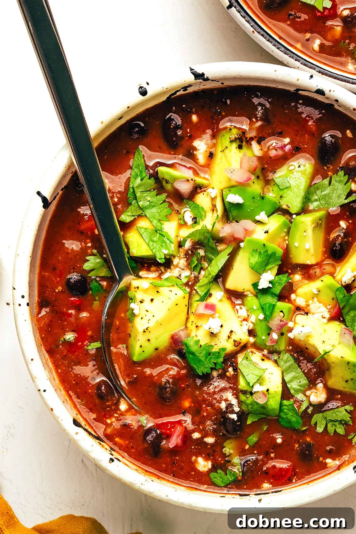 Hearty Black Bean Soup in a Bowl, garnished with cilantro and avocado