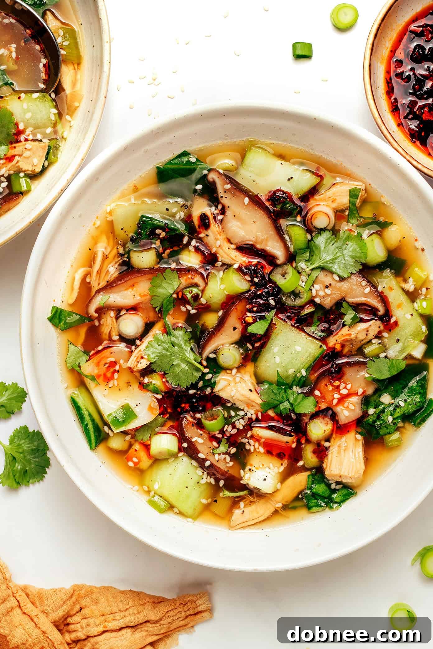 Overhead shot of two bowls of ginger scallion chicken soup, garnished beautifully.