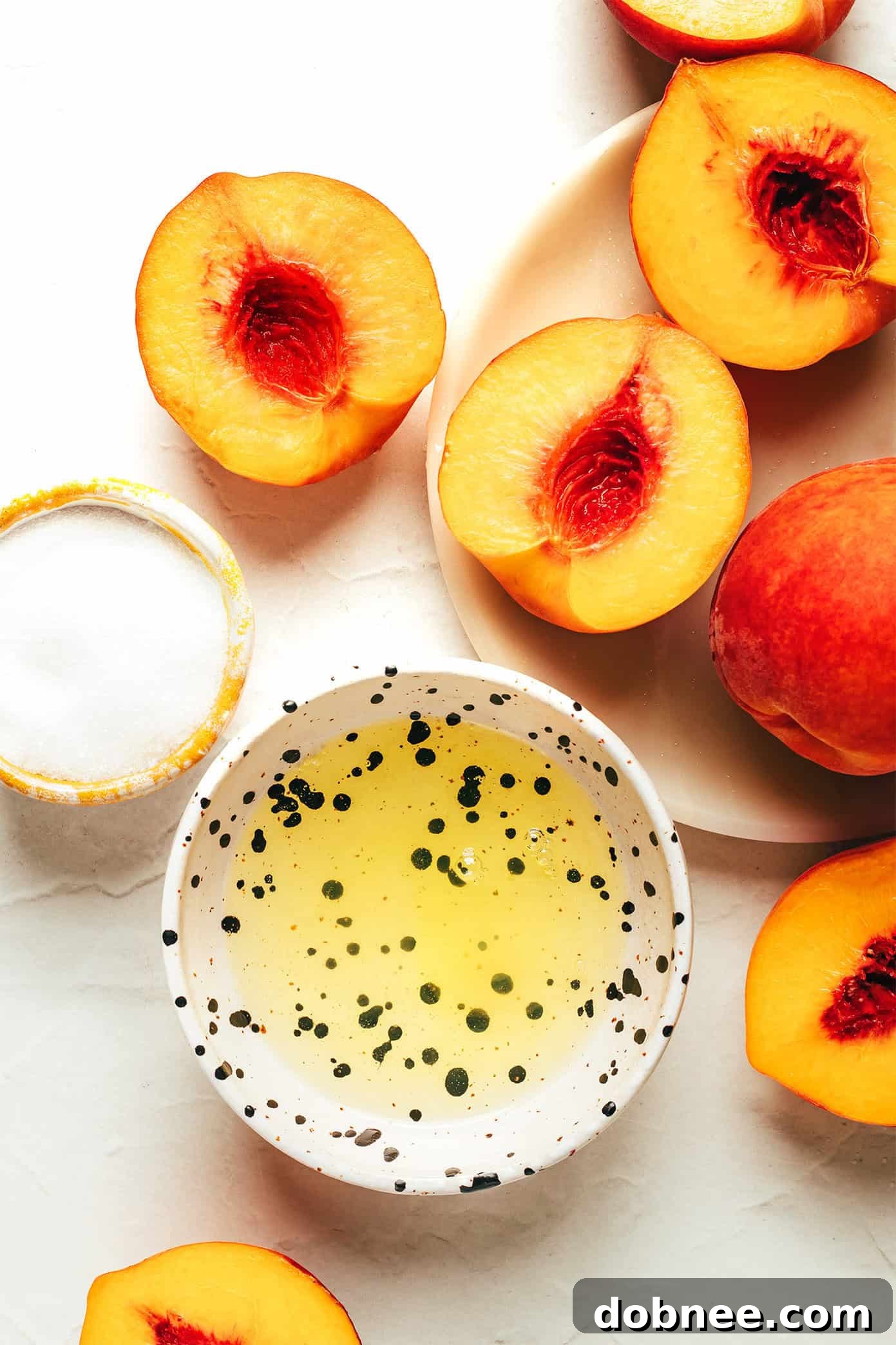 Two halves of broiled peaches topped with meringue on a baking sheet.