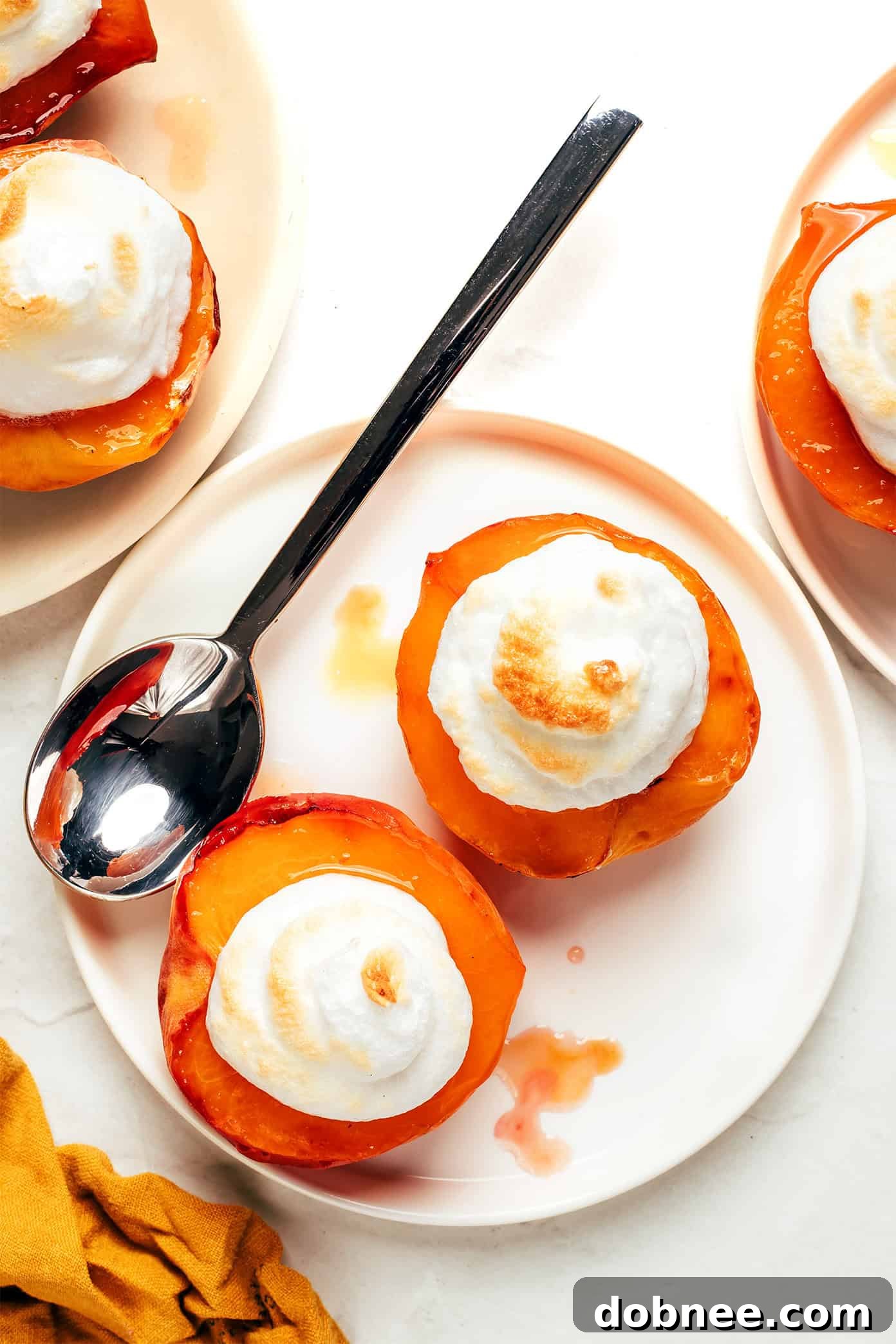 A bowl of foamy egg white meringue next to broiled peach halves.