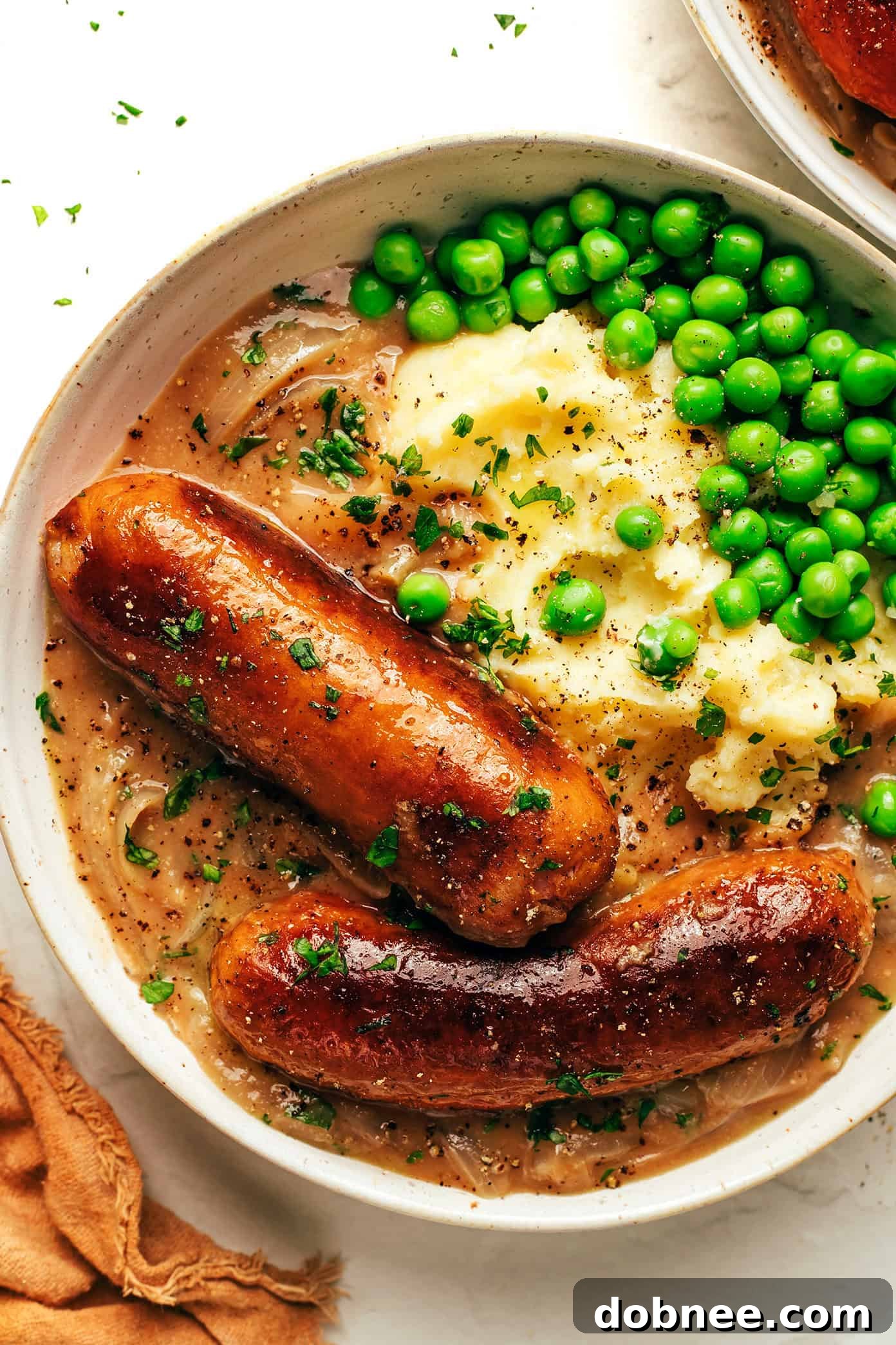 British Comfort Classic 2 Golden brown sausages served with creamy mashed potatoes and a generous helping of rich onion gravy.