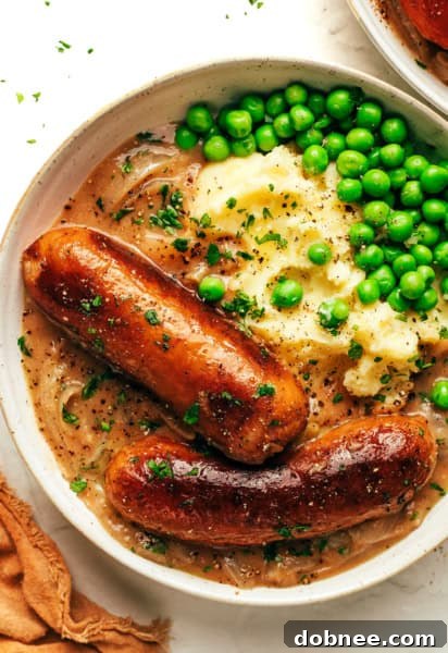 Bangers and mash plated with a side of peas, ready to be enjoyed.