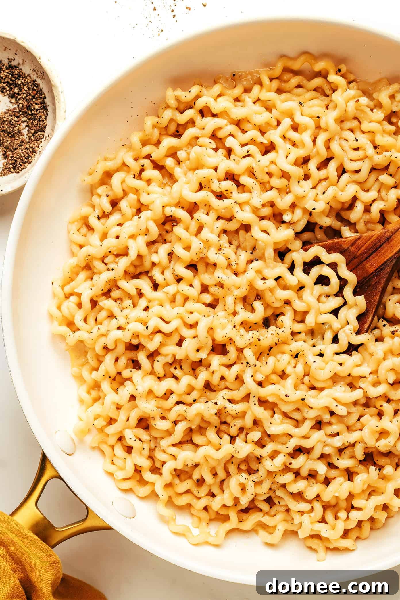 A close-up shot of a plate of creamy garlic miso pasta, garnished with fresh herbs and a sprinkle of black pepper.