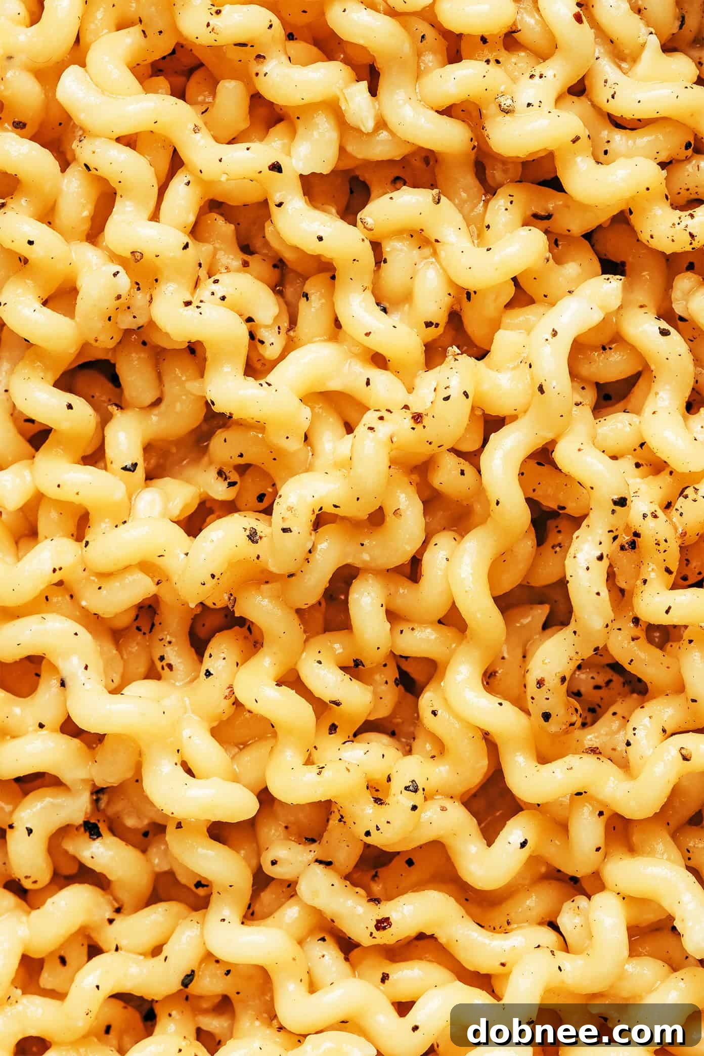 A neatly arranged plate of garlic miso pasta, topped with fresh parsley and a dash of black pepper, ready to be eaten.