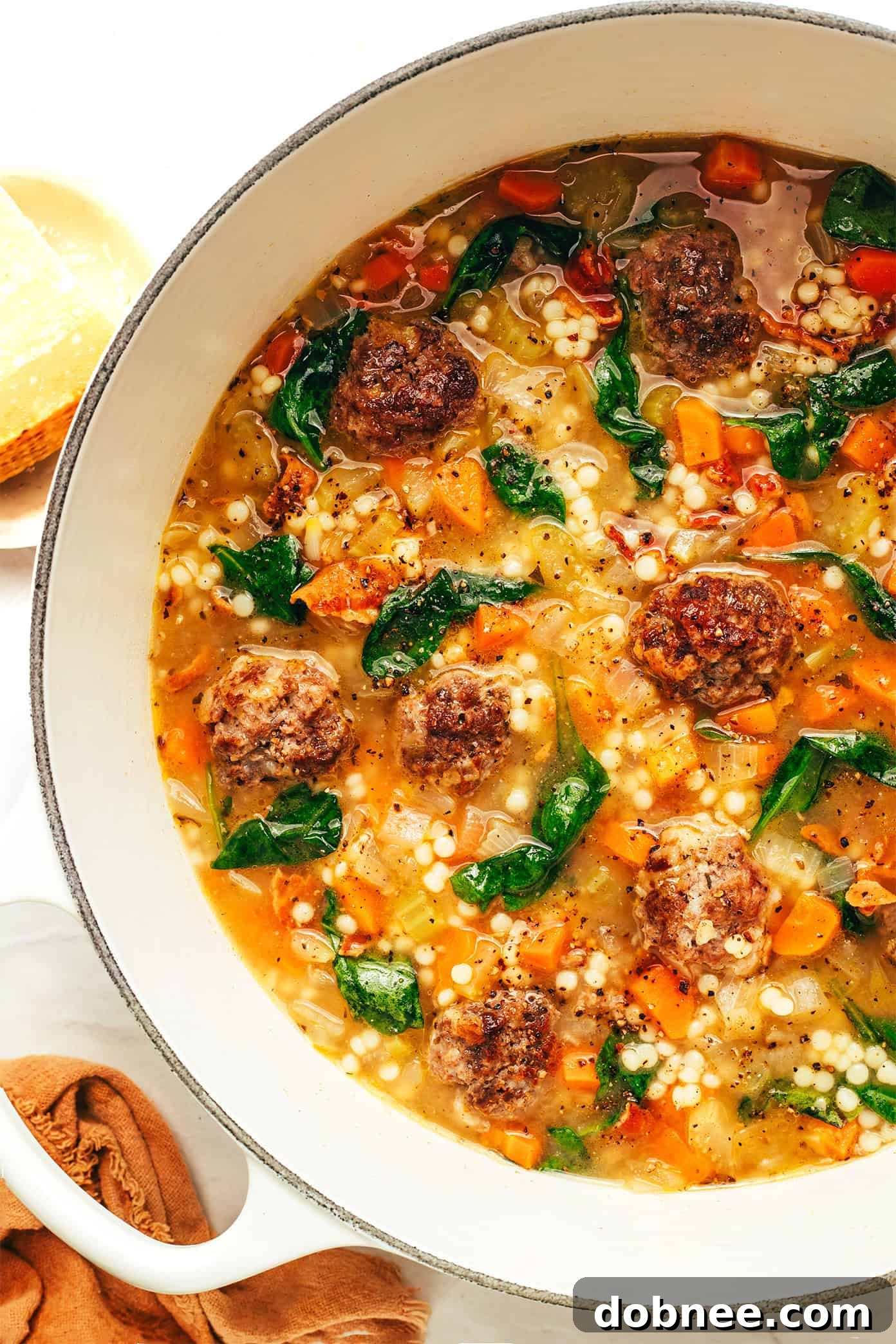 A ladle serving Italian Wedding Soup from a large pot