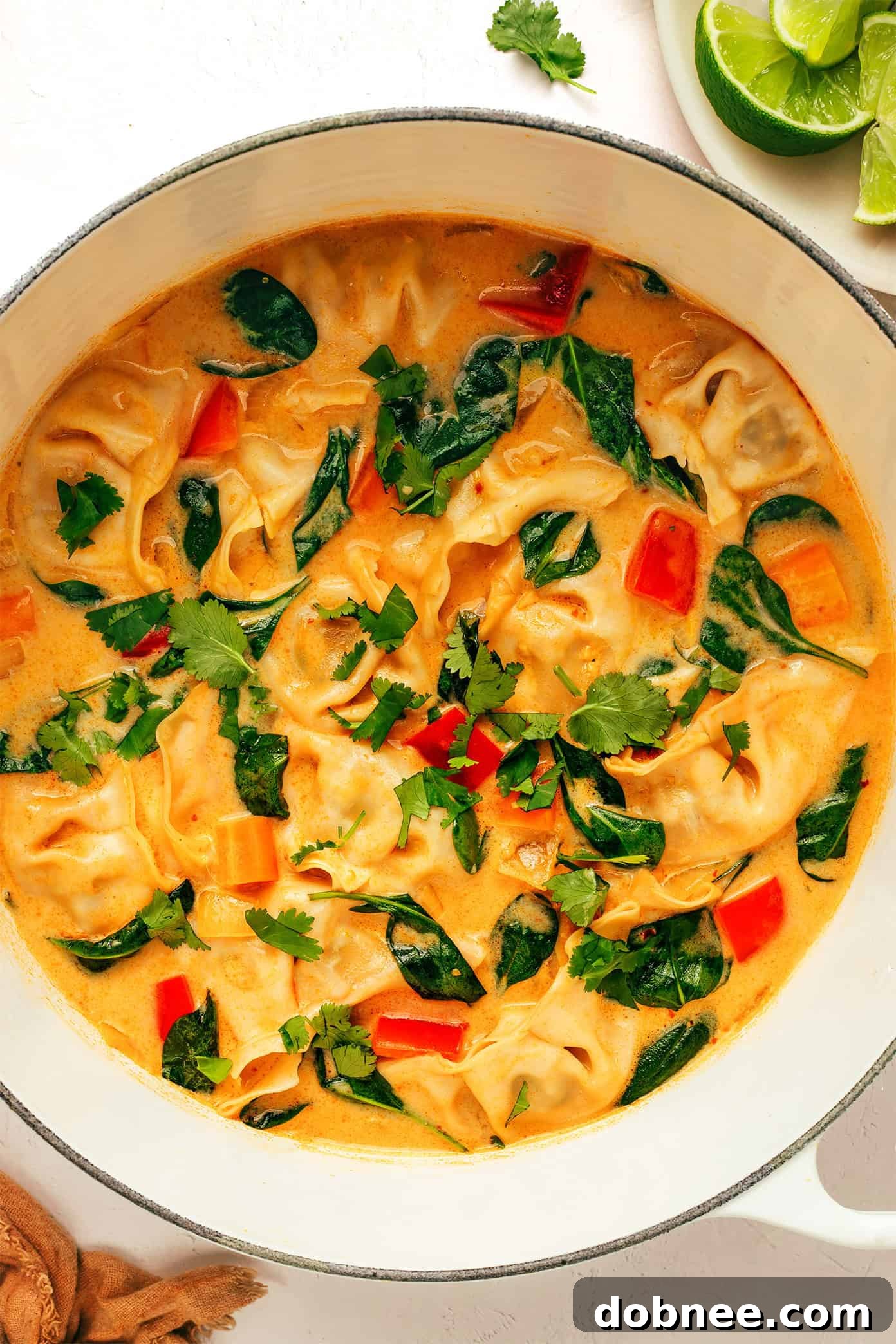 Four bowls of Thai Red Curry Potsticker Soup ready to be served, beautifully arranged with garnishes, highlighting its rich color and inviting texture.