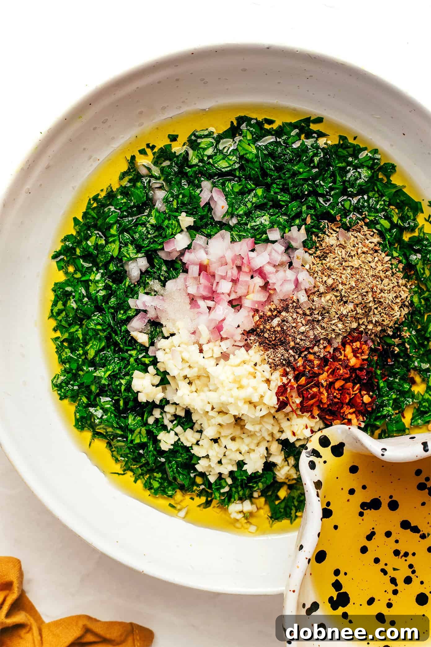 Chimichurri sauce being drizzled over grilled meat, showcasing its vibrant green color.