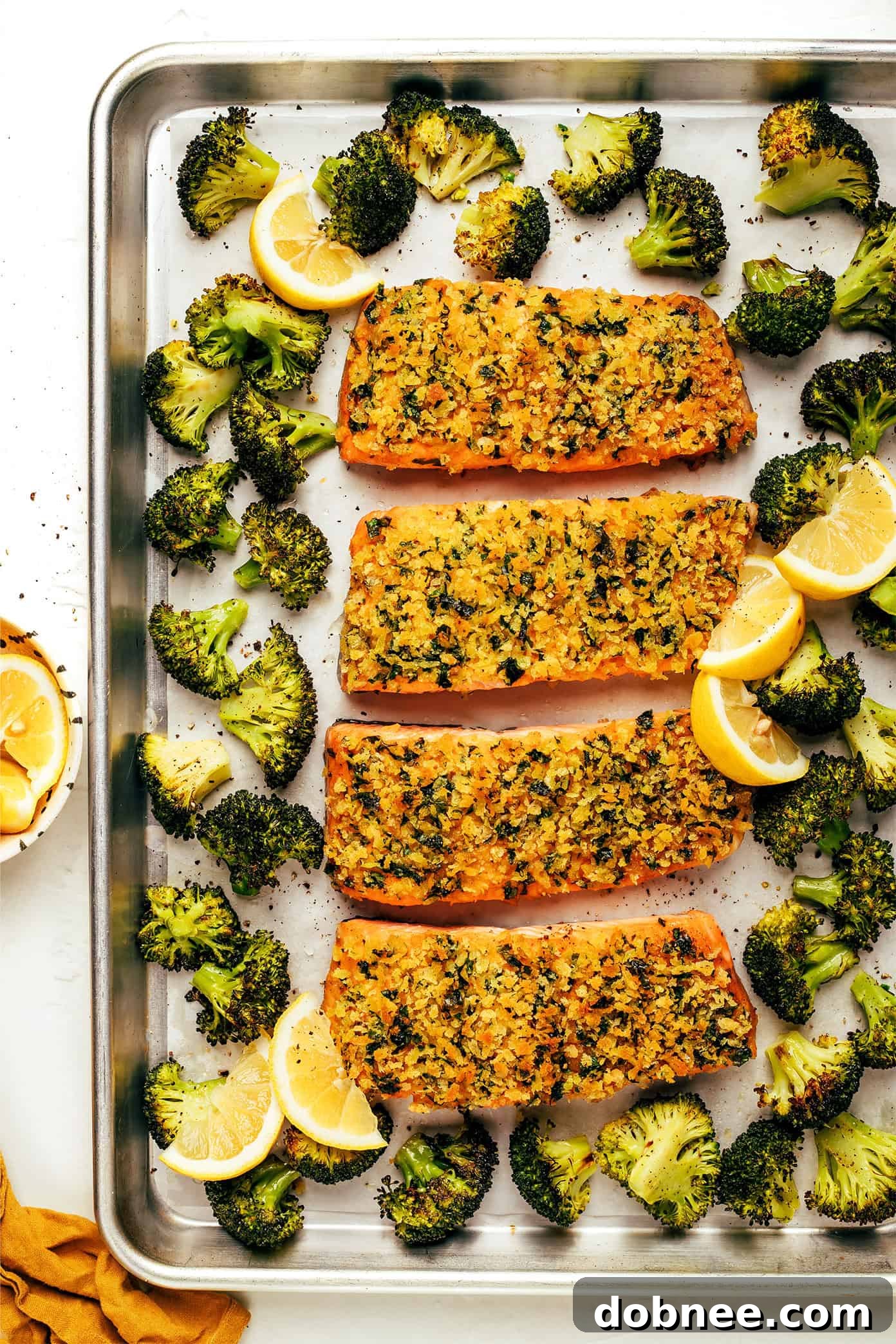 A close-up of crispy honey mustard salmon with broccoli and lemon wedges on a plate.