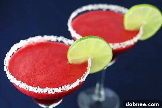 Vibrant Blackberry Lime Margarita in a glass, garnished with fresh blackberries and lime slices, set against a festive backdrop.