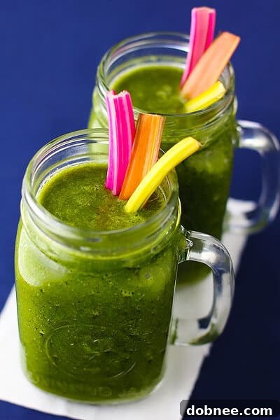 A glass of freshly made Rainbow Chard Banana Smoothie, garnished with a slice of banana, on a rustic surface.