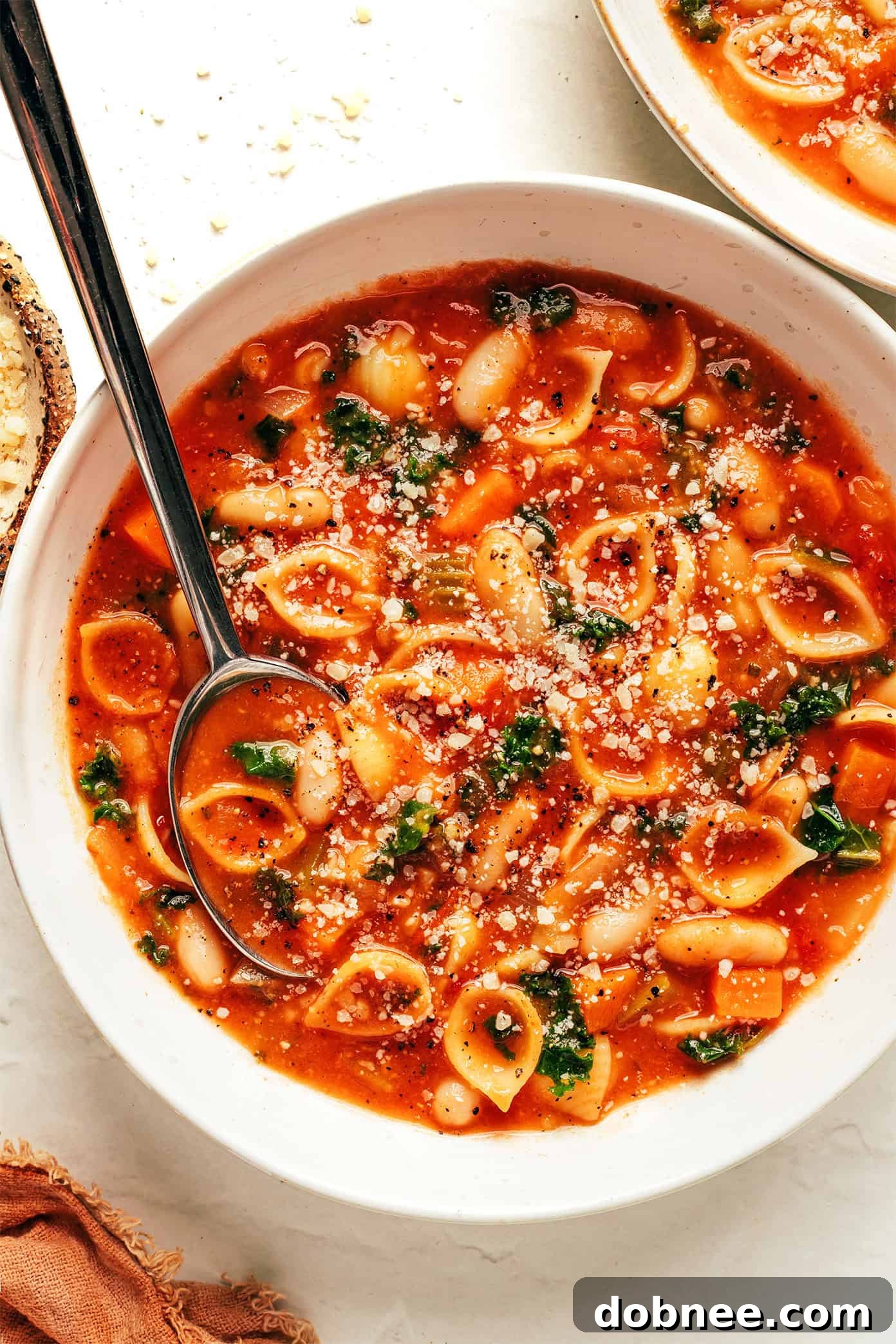 A steaming bowl of homemade Pasta e Fagioli, garnished with fresh parsley and Parmesan cheese, ready to be enjoyed.