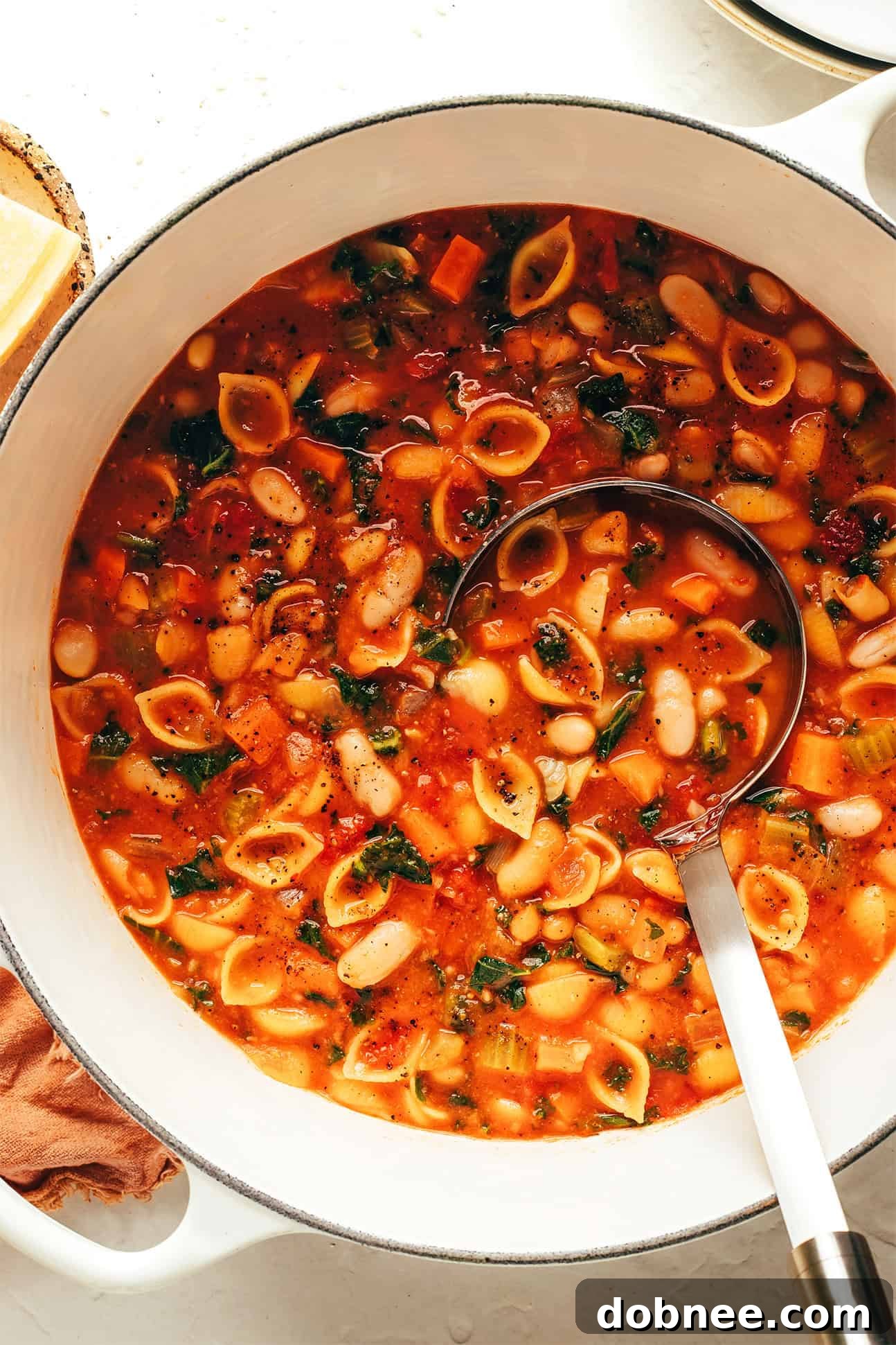 A close-up of a wooden spoon scooping up a portion of the hearty Pasta e Fagioli soup.