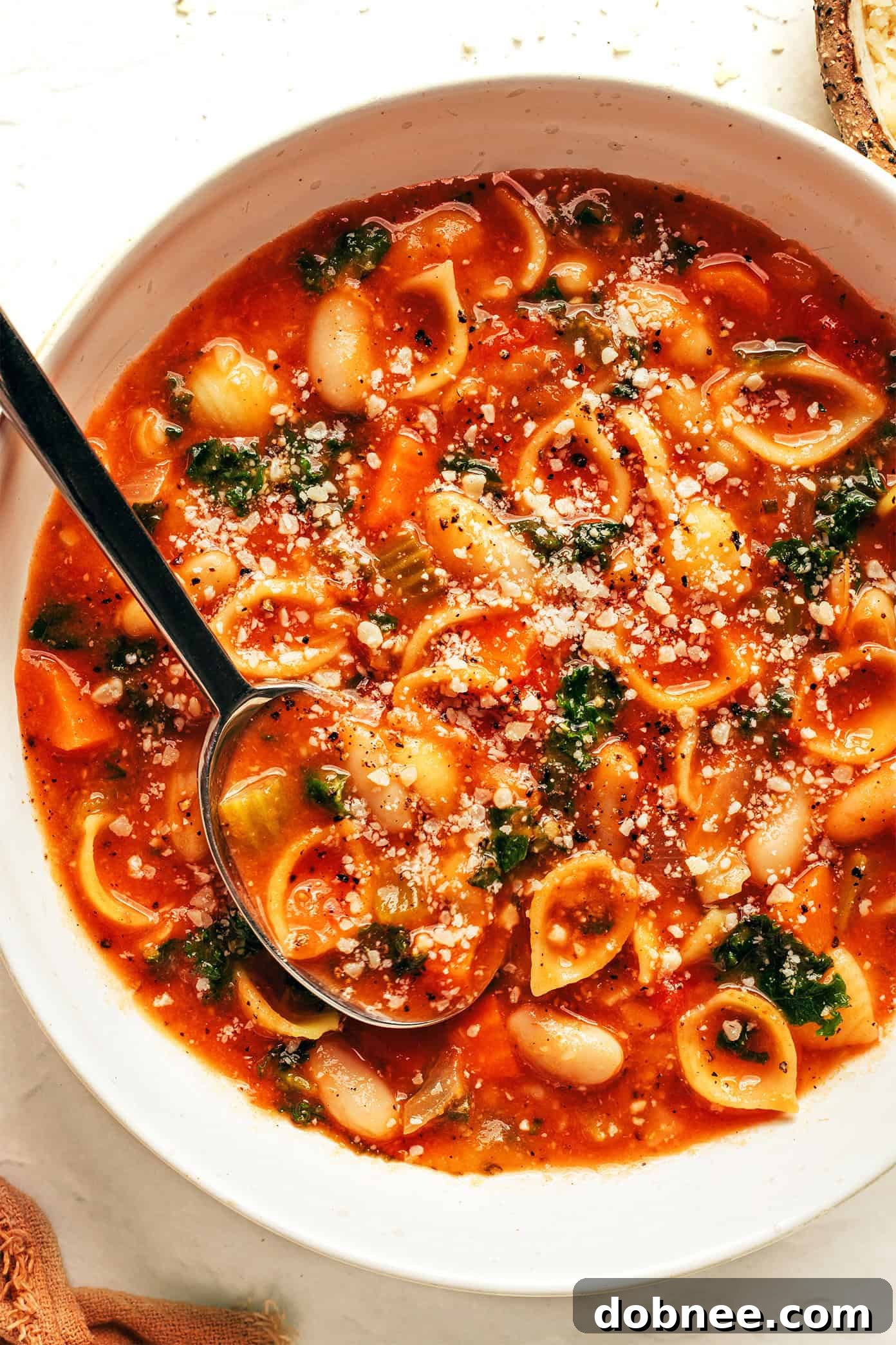 A final overhead shot of a table laden with Pasta e Fagioli, crusty bread, and a side dish, inviting viewers to share a meal.