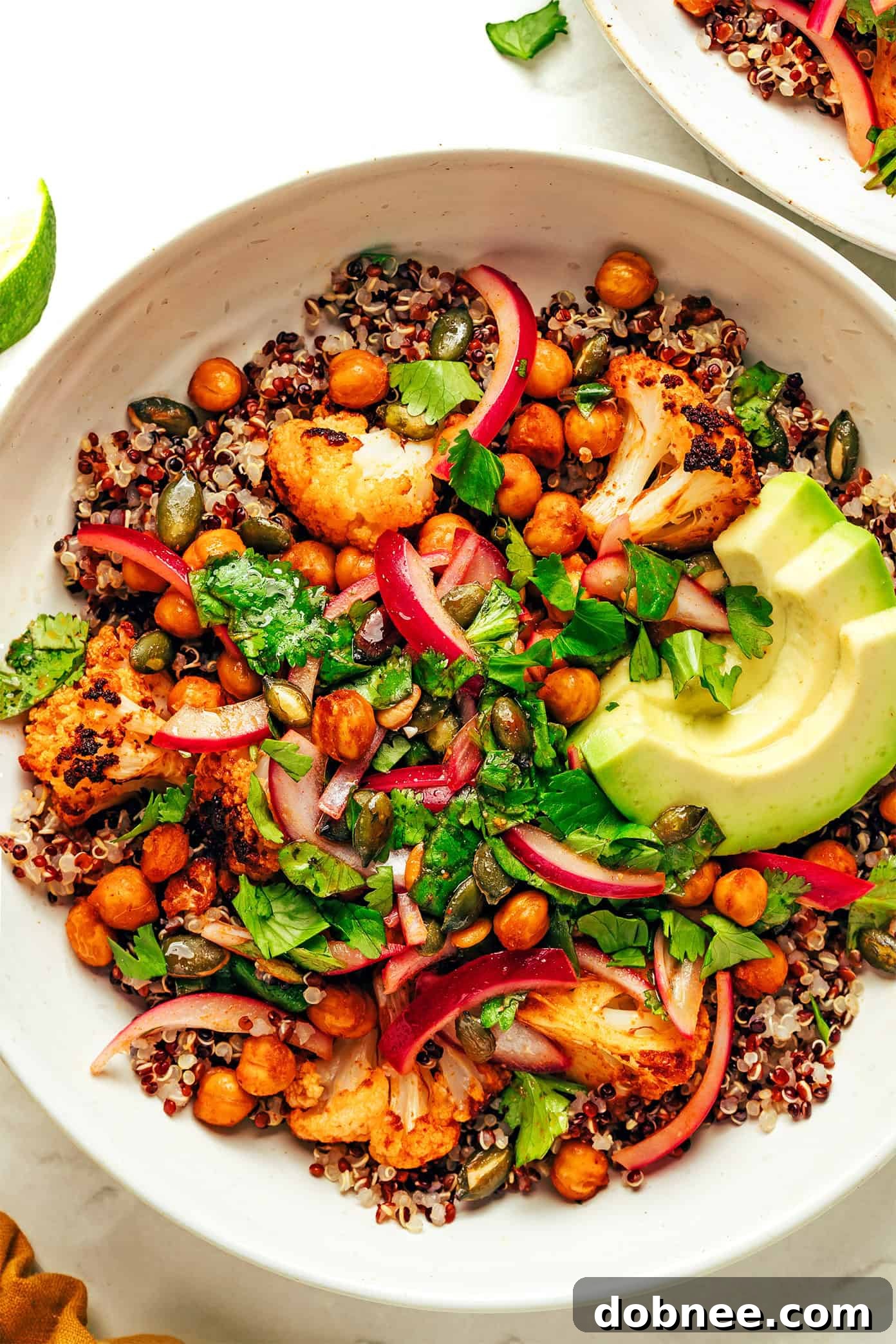 A close-up of roasted cauliflower and chickpeas on a parchment-lined baking sheet, showing their golden brown and crispy texture.