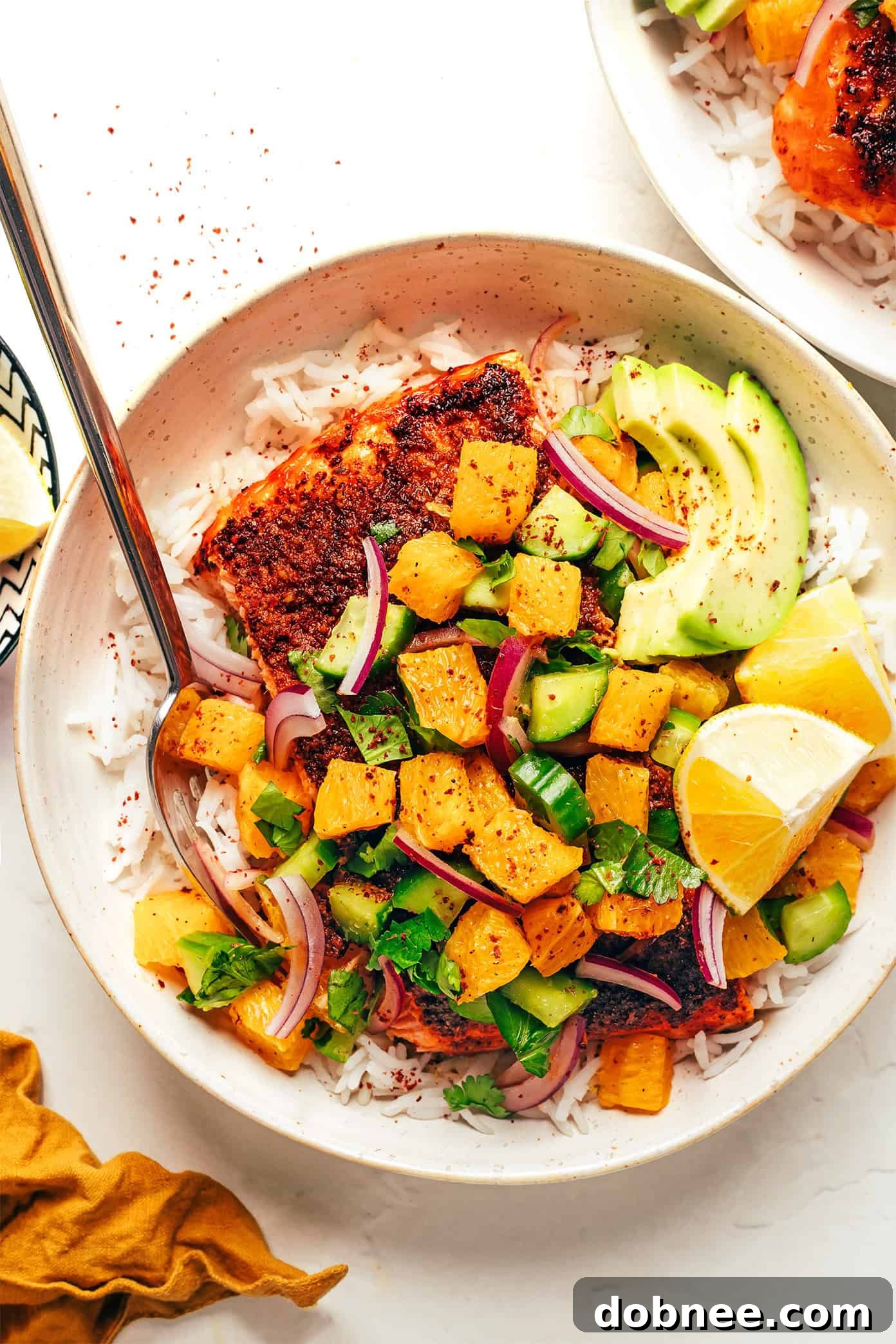 Sumac Blackened Salmon served on a plate with rice, avocado, and citrus salsa