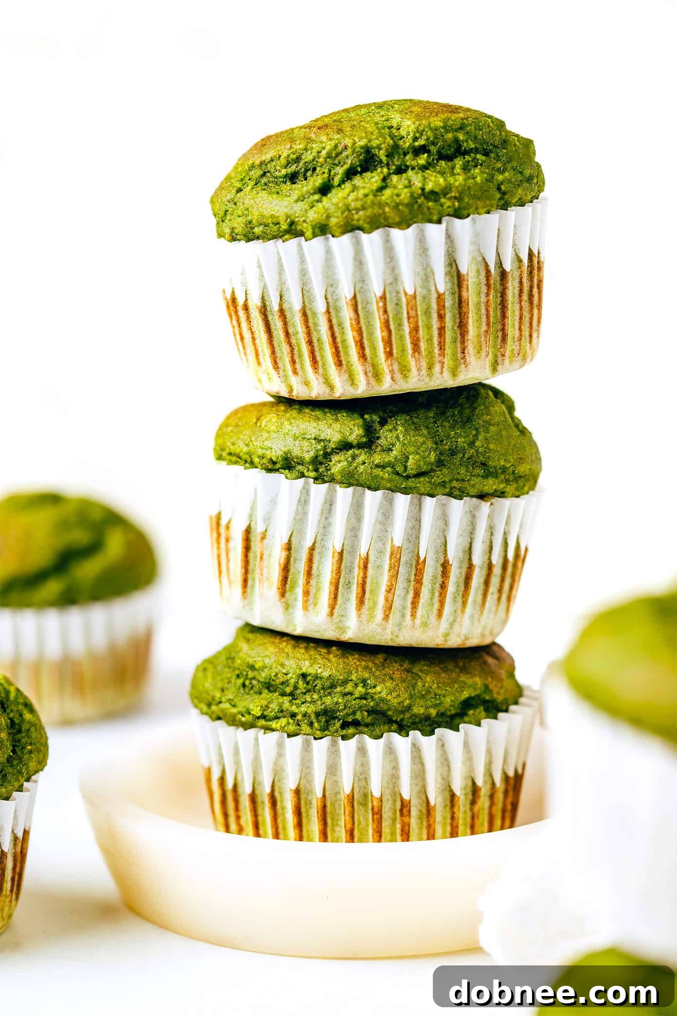 Stack of Healthy Blender Spinach Banana Muffins green muffins in a stack on a white plate