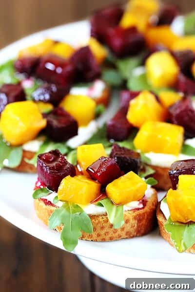 Close-up of a beautifully assembled Roasted Beet, Arugula, Goat Cheese & Honey Crostini, showcasing the vibrant colors and fresh ingredients.