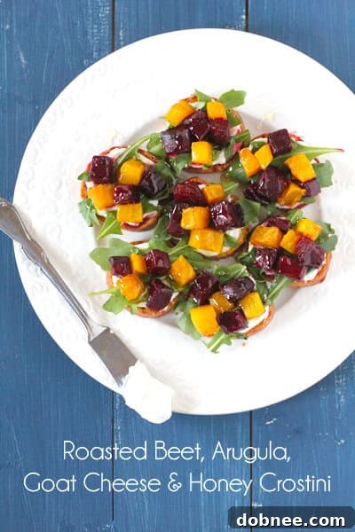 Two pieces of Roasted Beet, Arugula, Goat Cheese & Honey Crostini on a serving plate, ready to be enjoyed as a gourmet snack.
