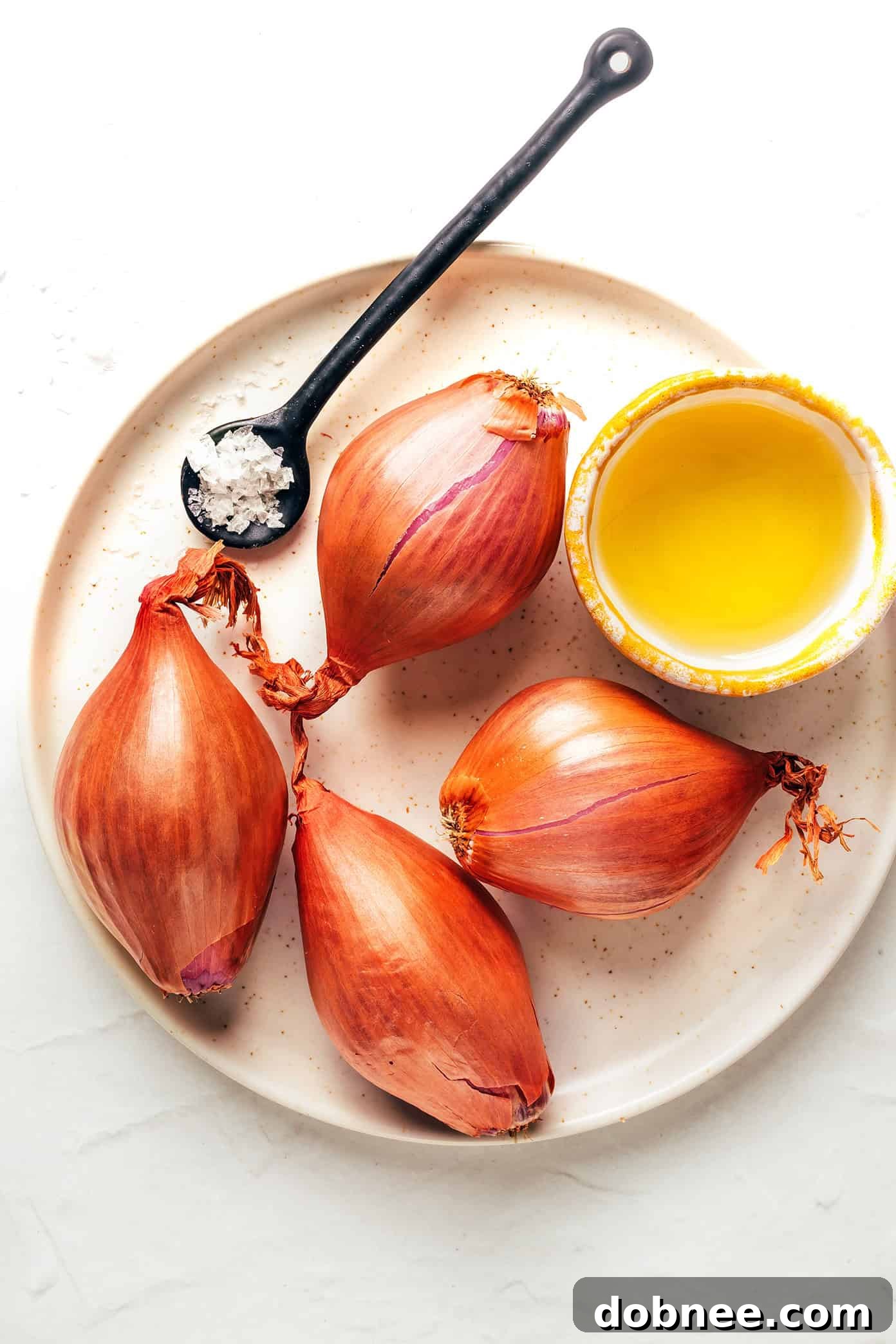 Crispy shallots being scooped from a hot pan with a slotted spoon.