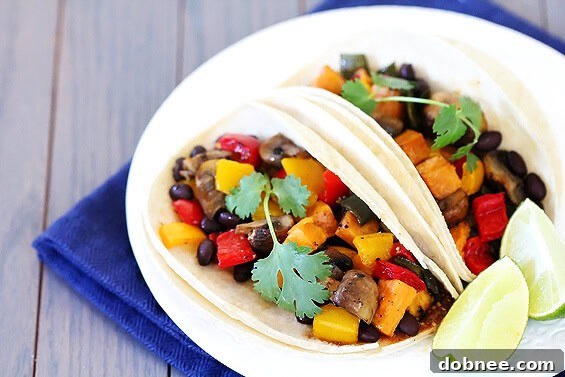 Serving of roasted vegetable and black bean tacos with a side of lime