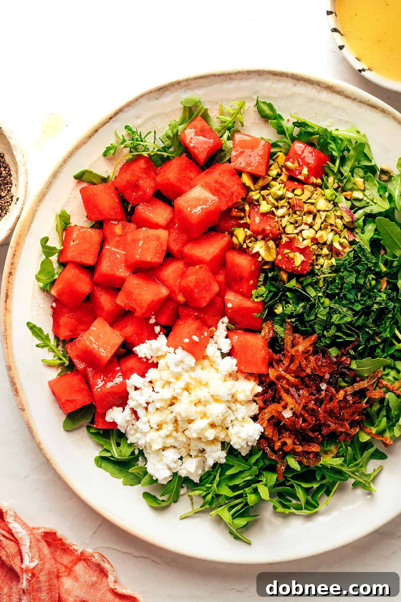 Watermelon arugula salad in a bowl with dressing