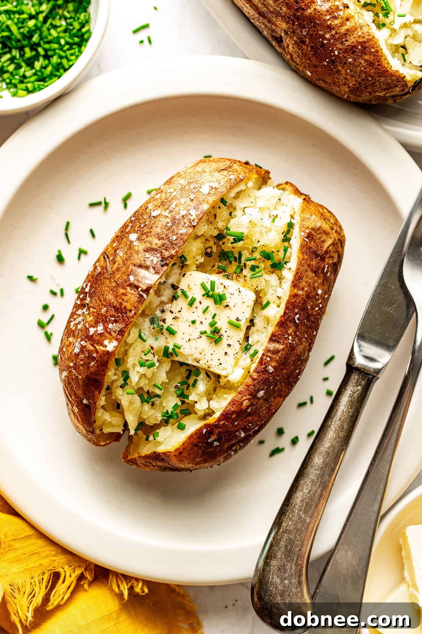 Air fryer baked potato served simply with butter and fresh chives, a timeless classic.