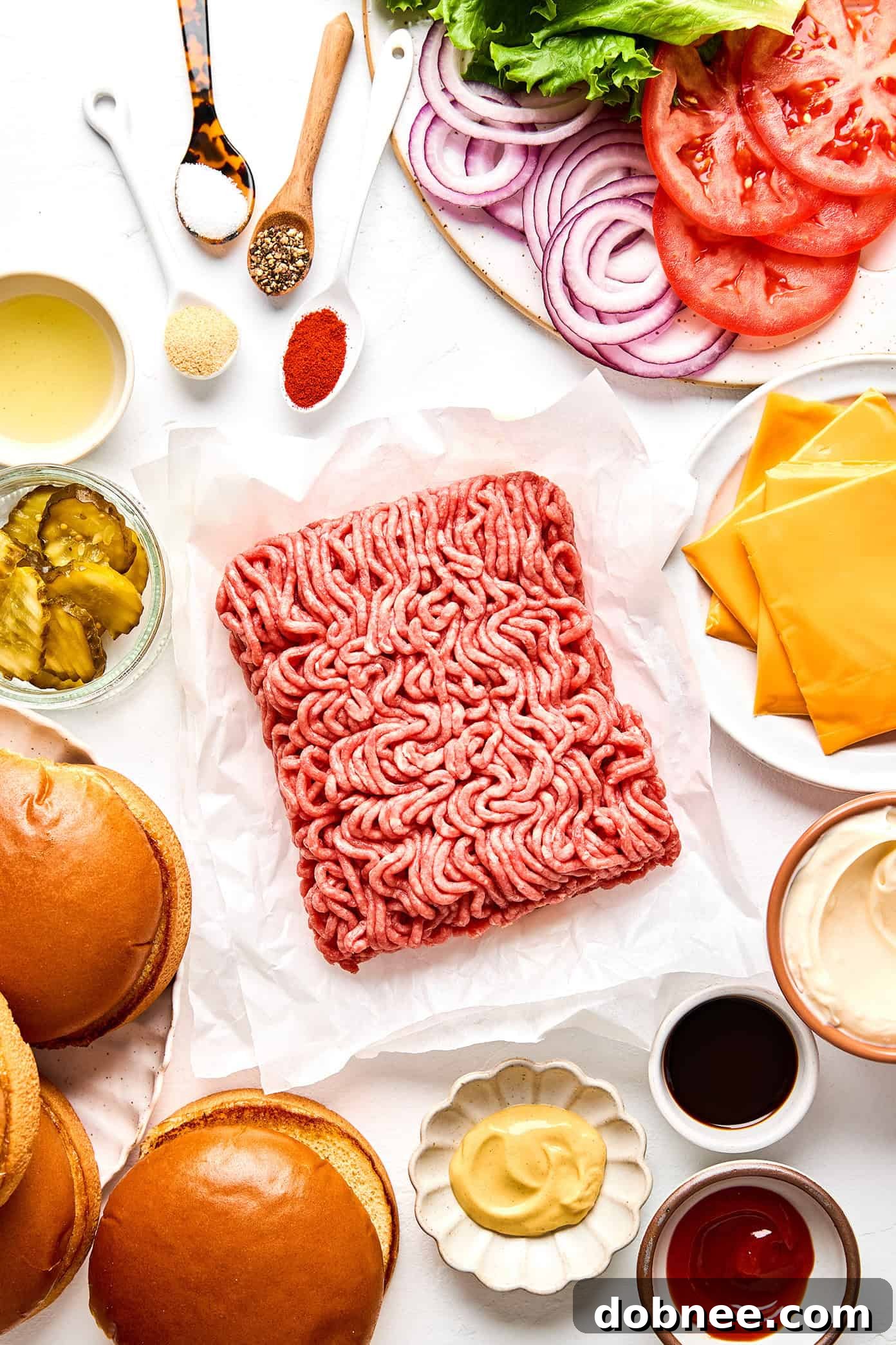 Ingredients laid out for making smash burgers including ground beef, cheese, buns, and spices