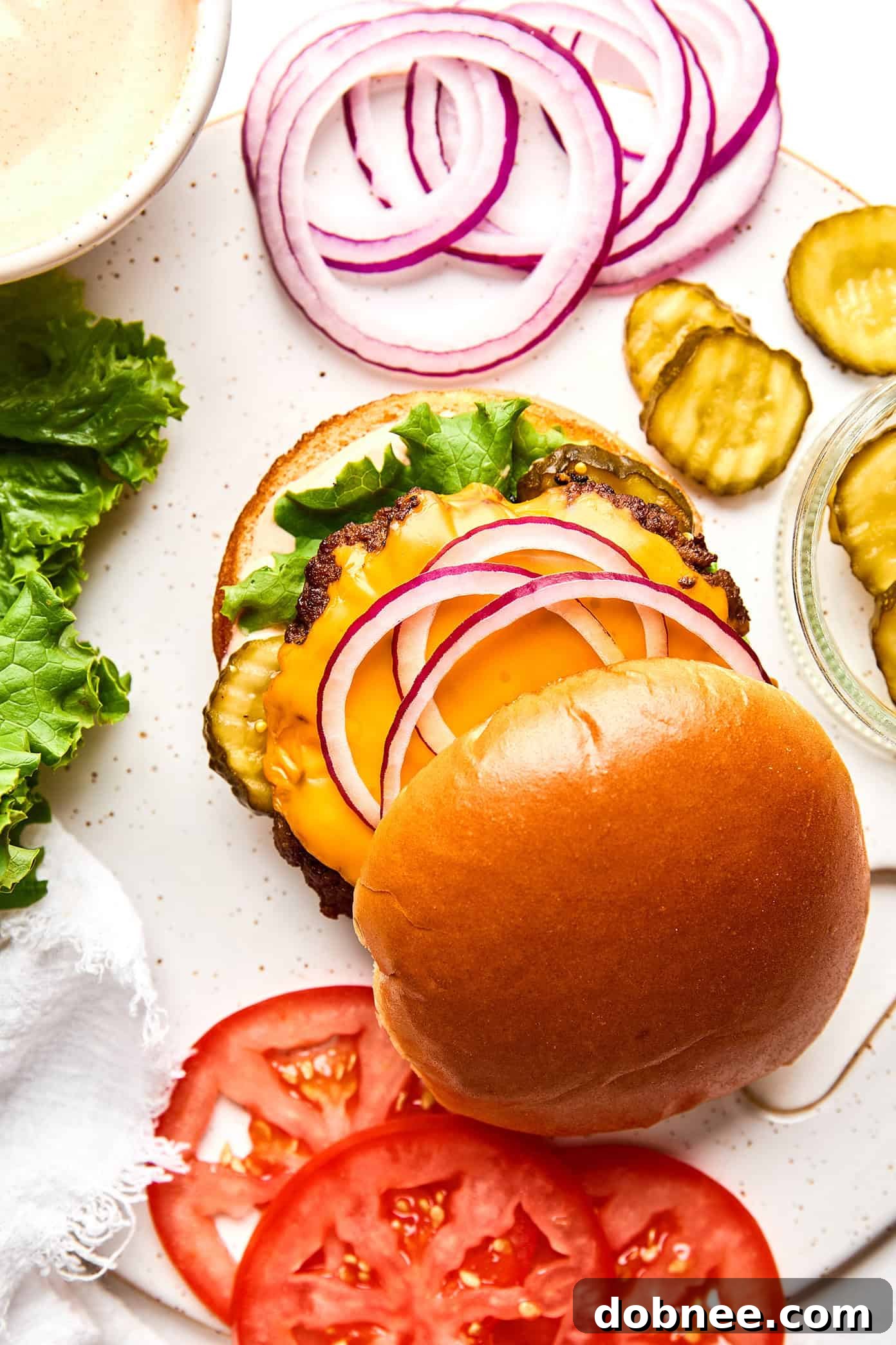 A beautifully assembled smash burger with all the toppings, ready to be eaten