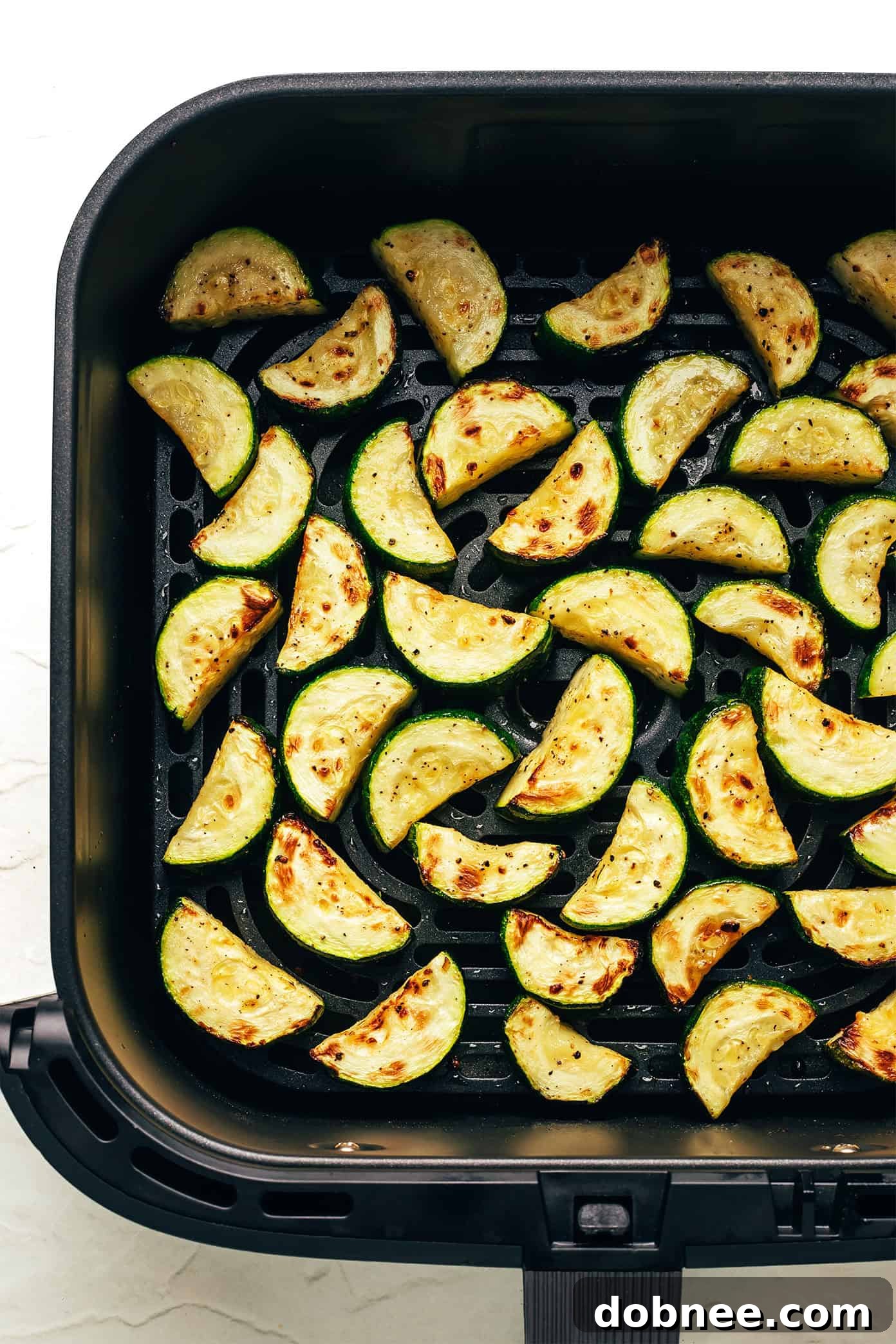 Air Fryer Zucchini in an air fryer basket, freshly cooked