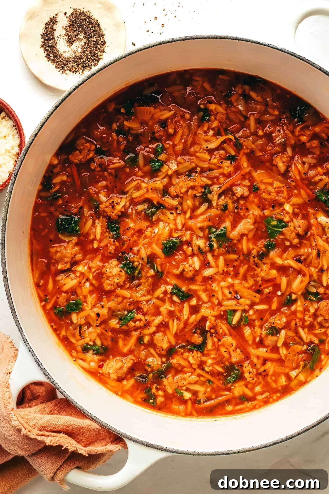 A large pot of Cabbage Sausage Orzo Soup with a ladle, ready to be served.