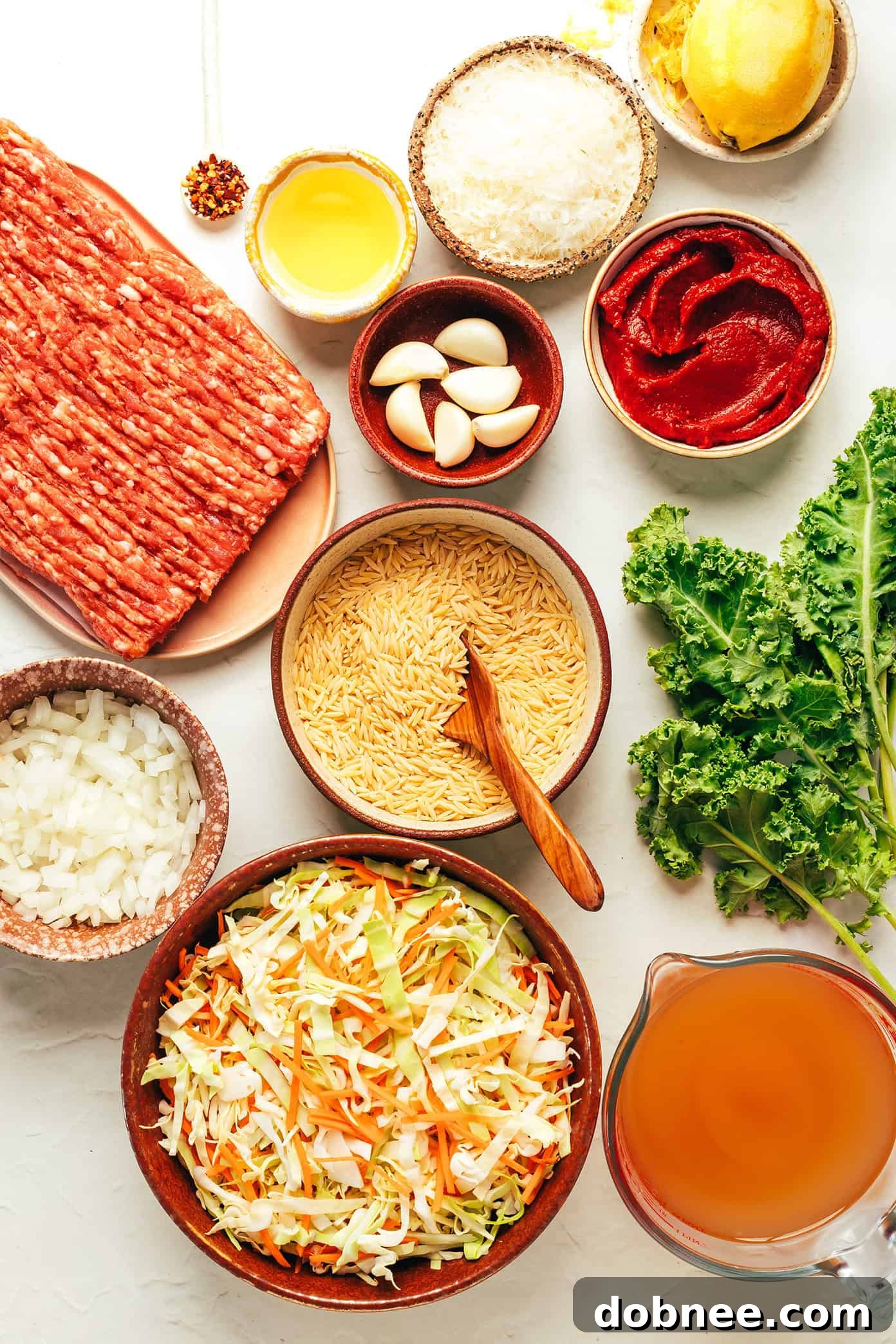 Sausage and orzo soup simmering in a Dutch oven with vegetables.