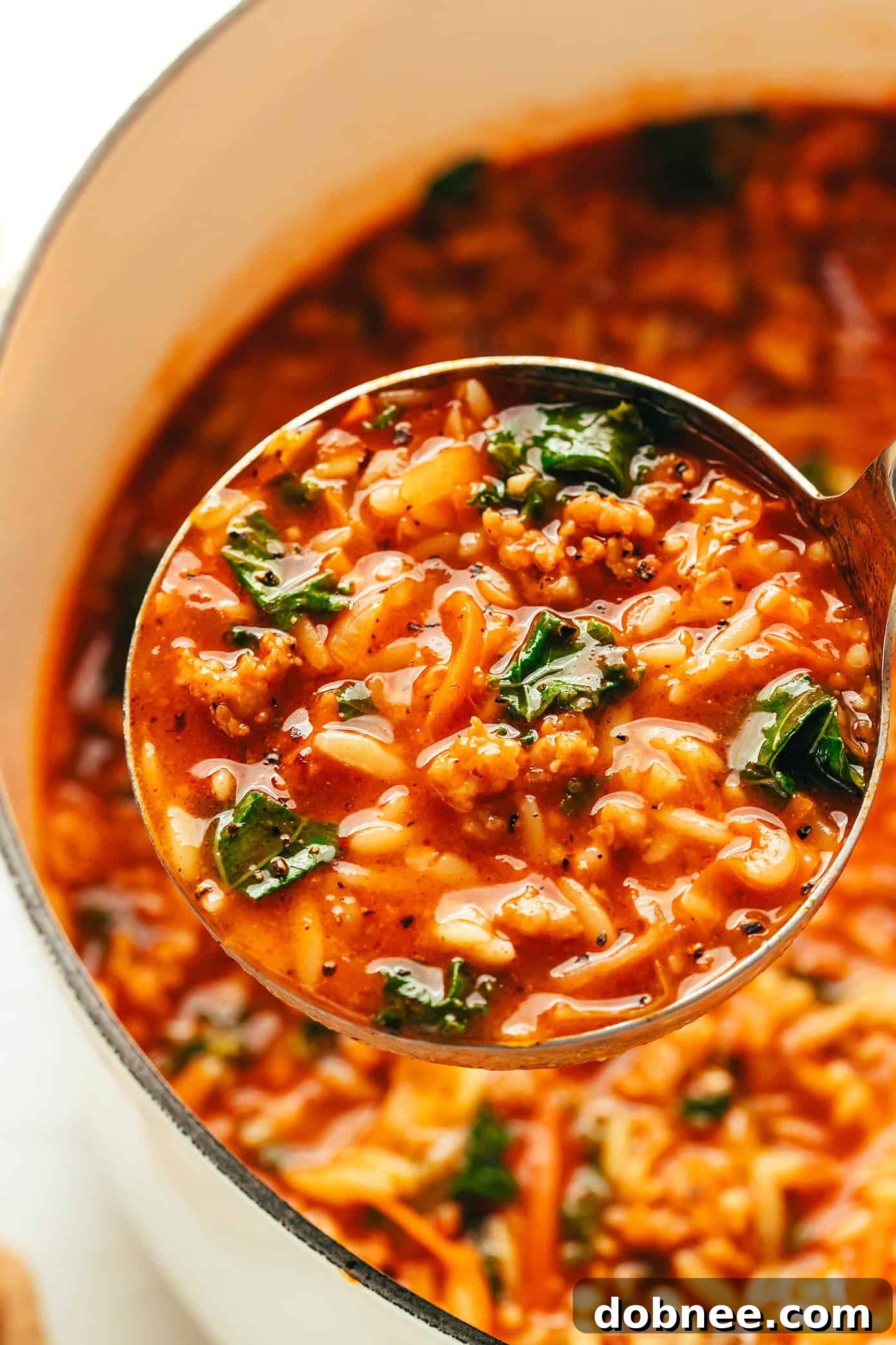 Four bowls of Cabbage Sausage Orzo Soup on a wooden table.