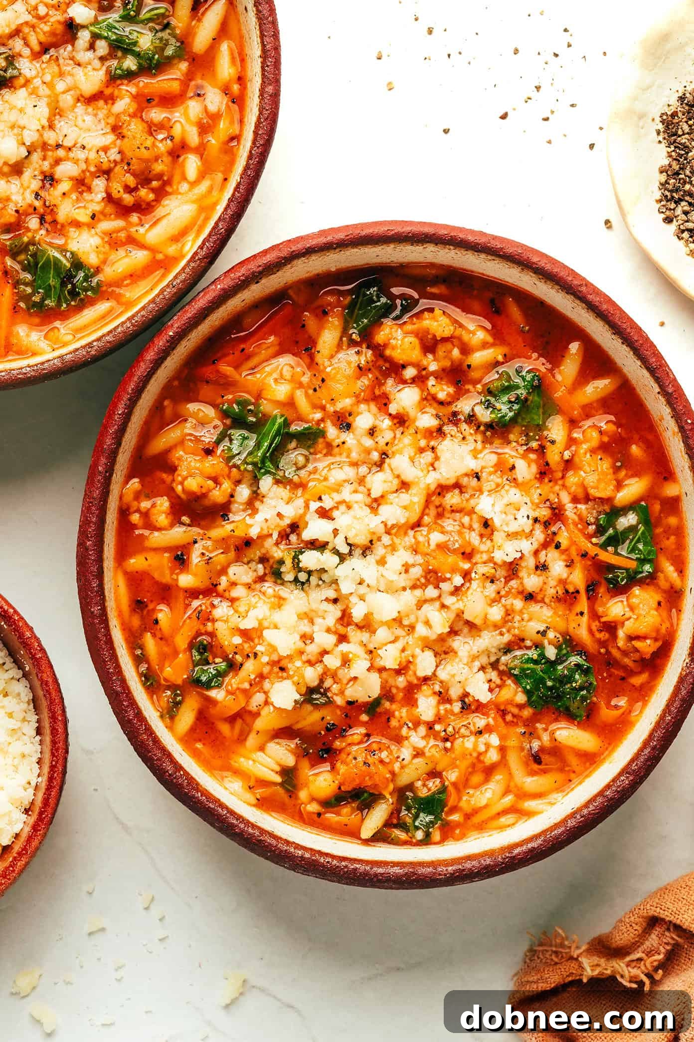 Five bowls of Cabbage Sausage Orzo Soup with a cozy background.
