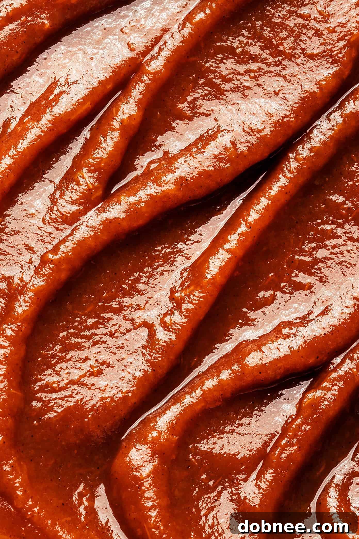 Various jars of homemade apple butter arranged on a table.