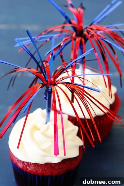 Three decadent Red Velvet Cupcakes topped with cream cheese frosting, presented on a rustic wooden surface with a festive backdrop.